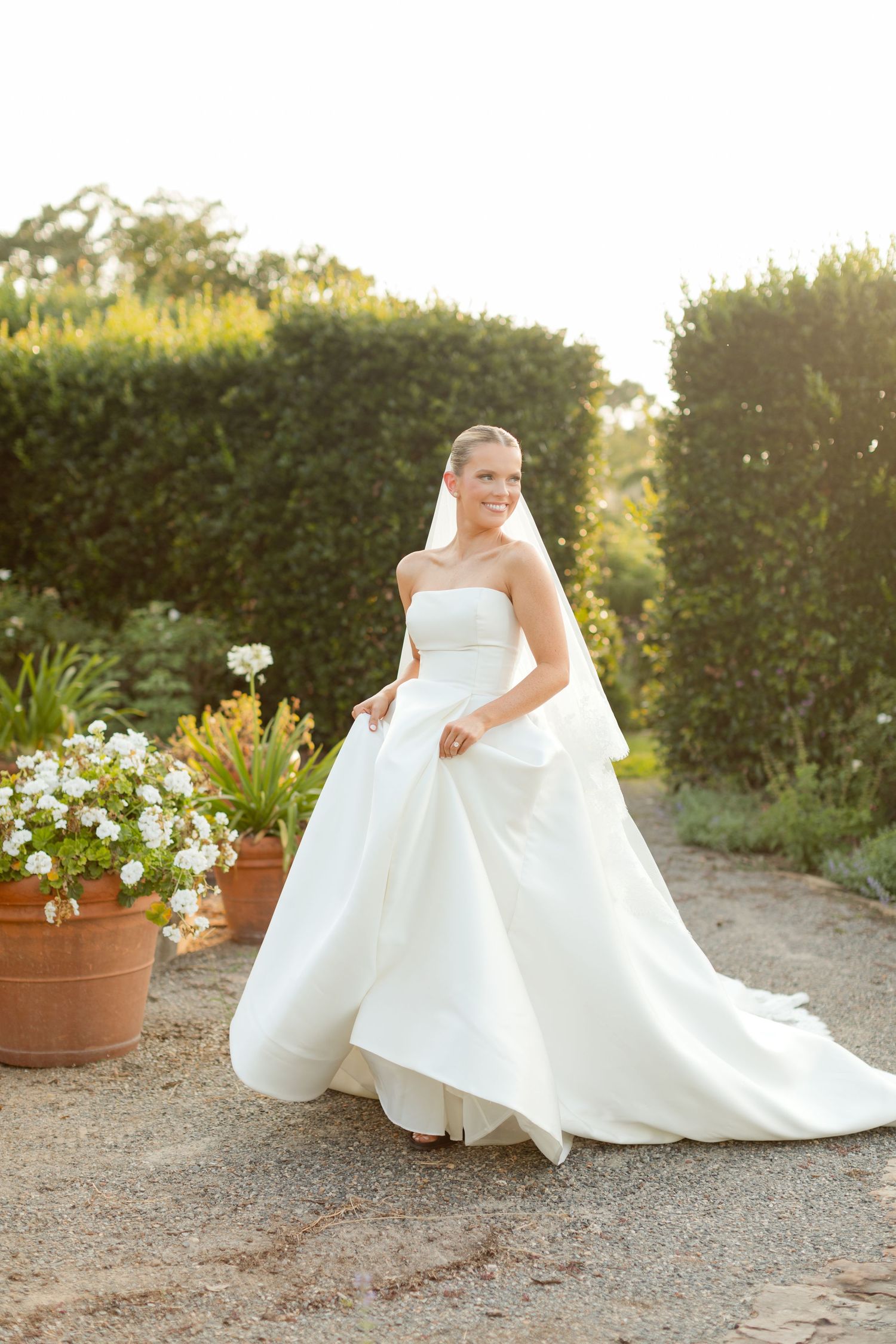 Series of four elegant white wedding dress photos showing flowing fabric and train against garden backdrop at sunset.
