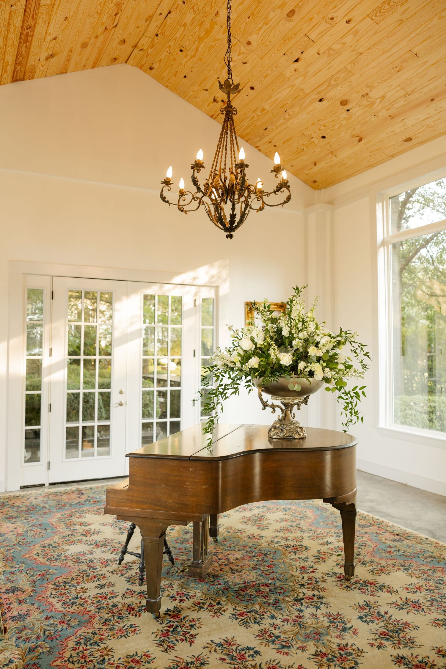 Elegant reception venue with wood plank ceiling, chandeliers, and floral patterned carpet.