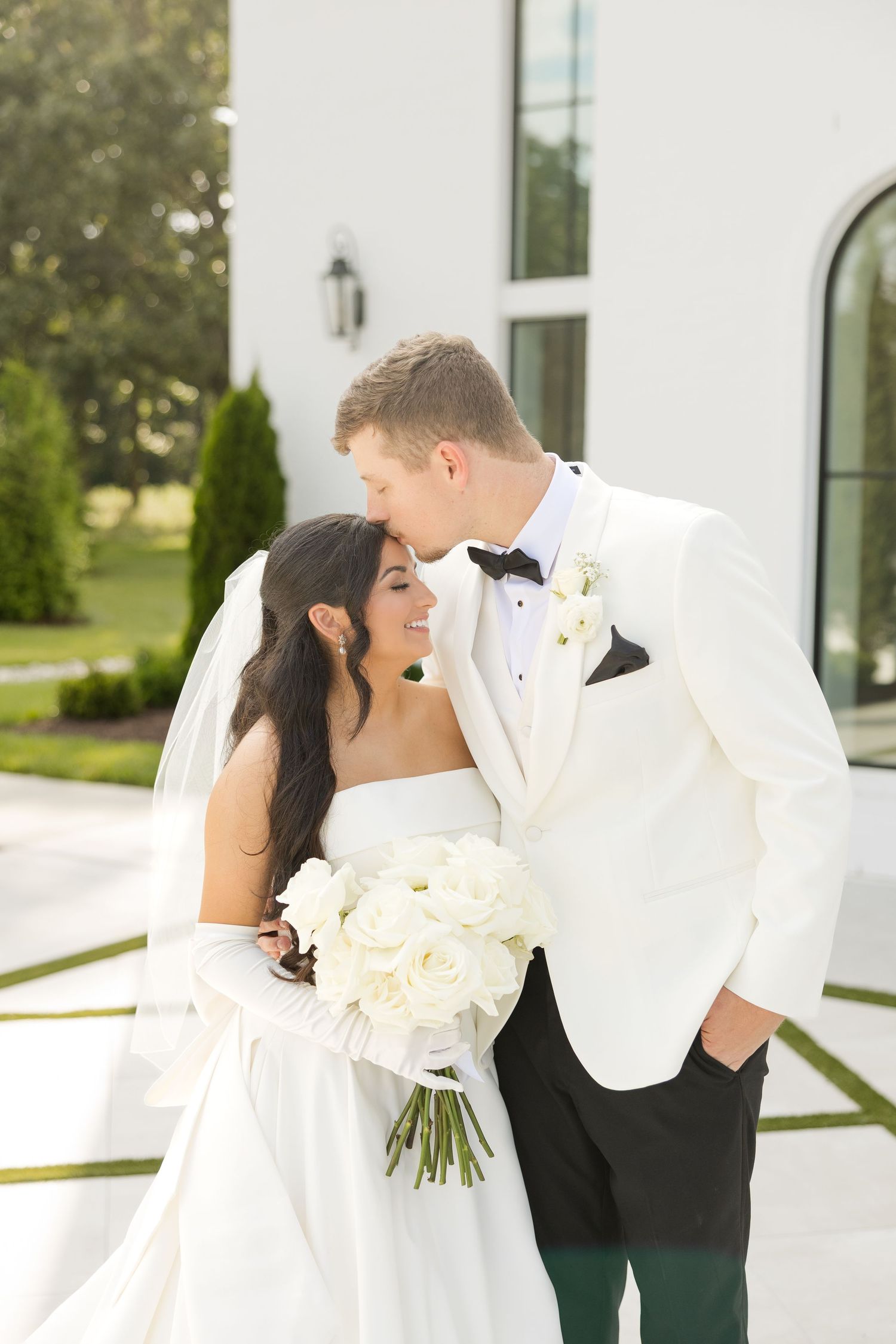 Wedding couple shares romantic moments outside a white chapel with classic architecture. Grand at the Springs.