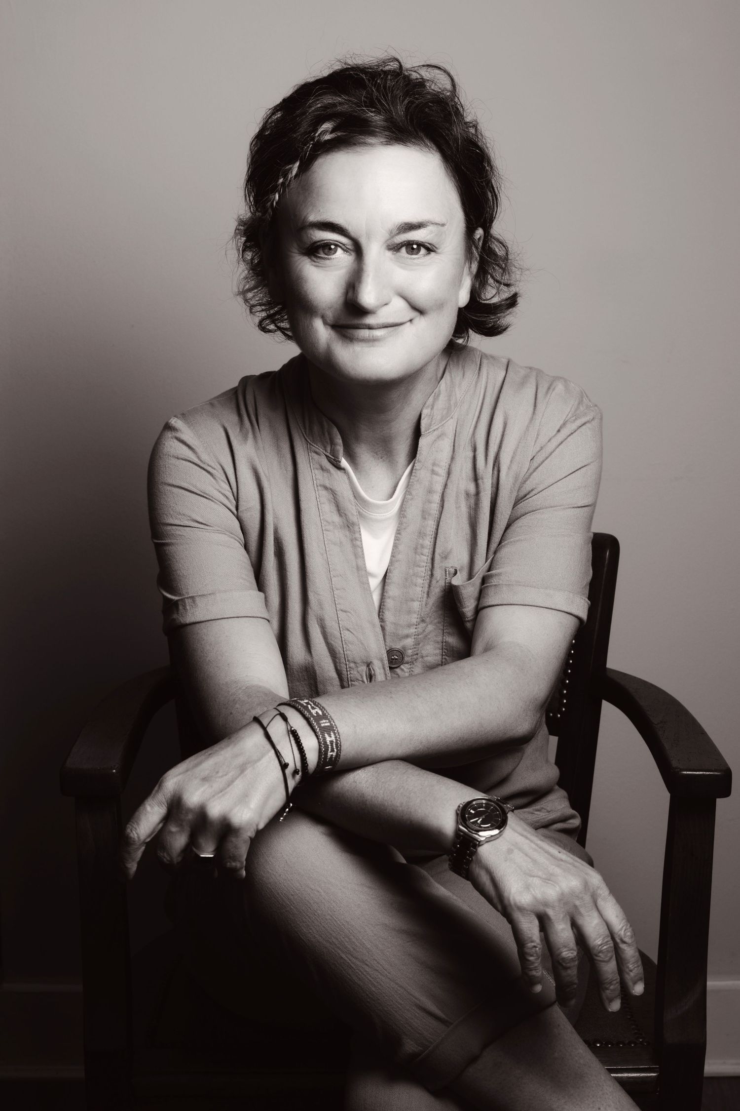 Black and white portrait of smiling woman seated in wooden chair.