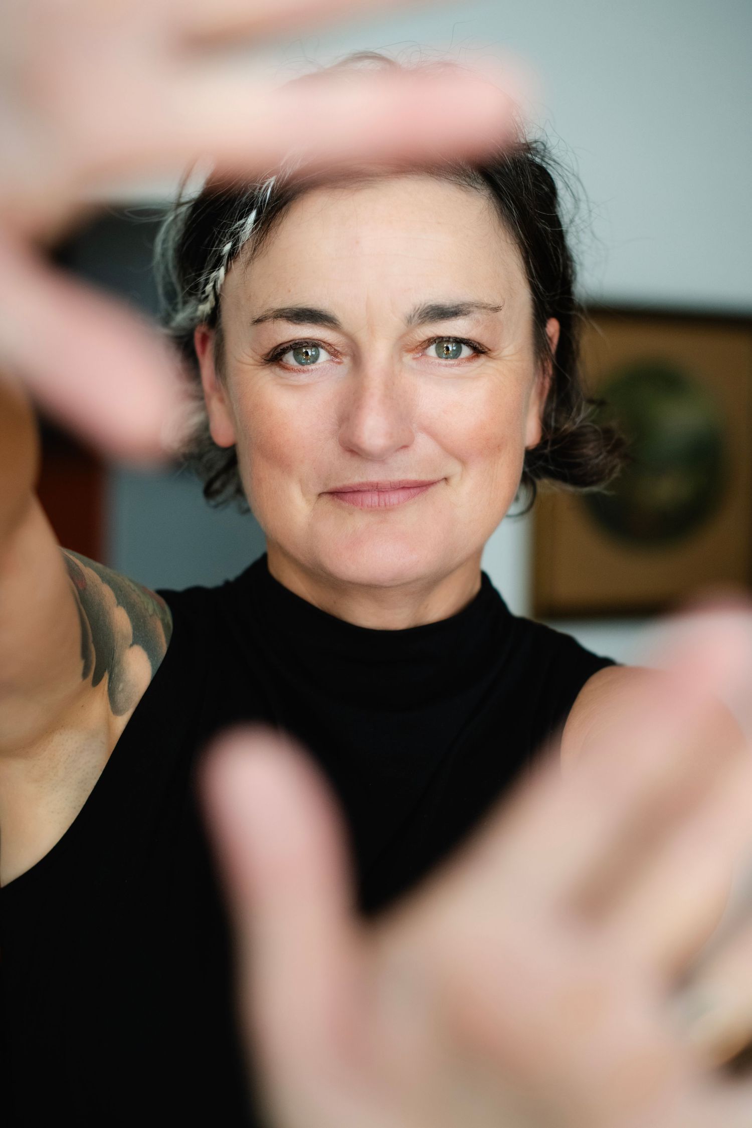 Woman framing face with hands creating finger frame portrait close-up.