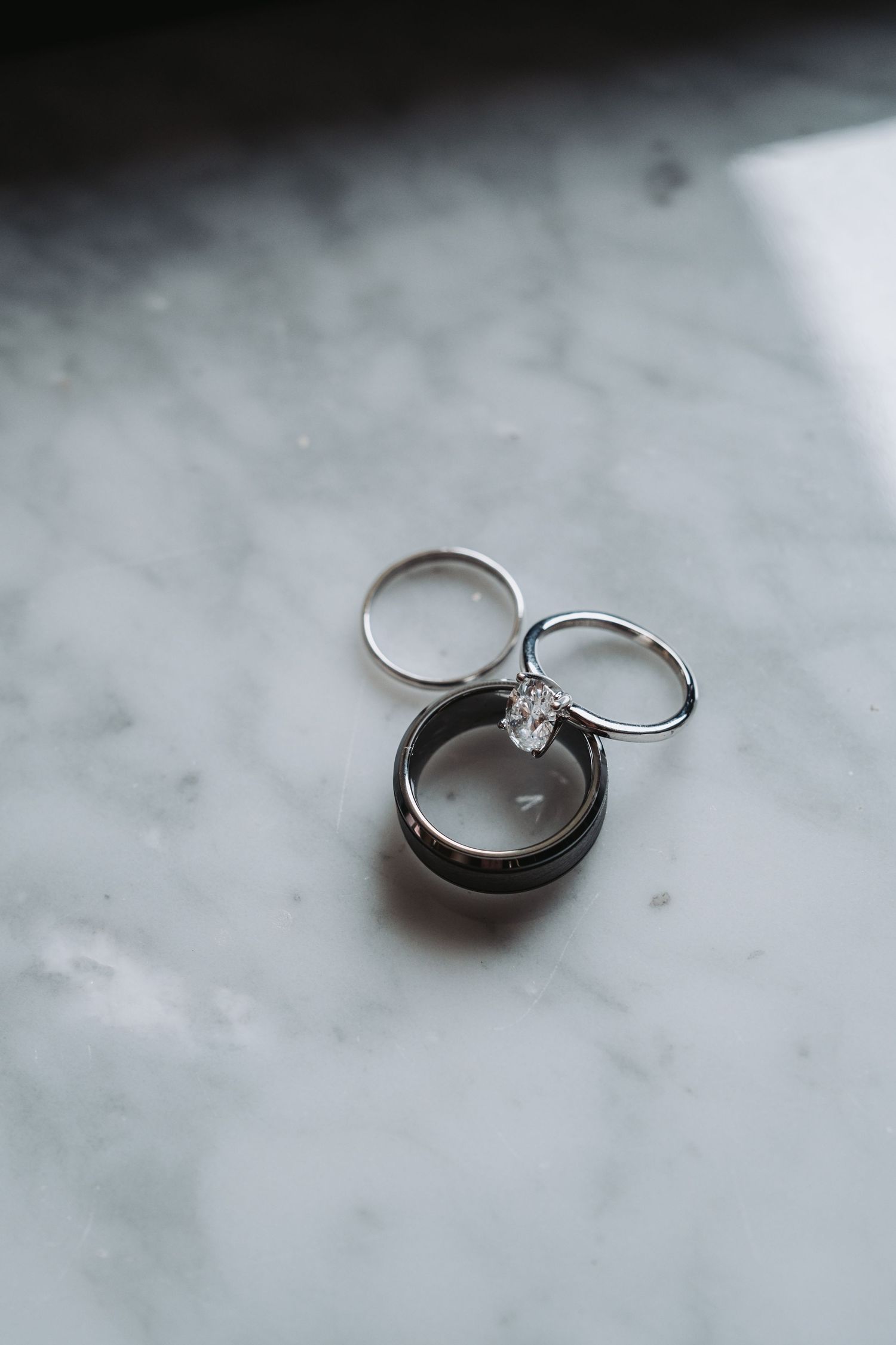 Close-up shots of elegant engagement rings with diamonds on a white marble surface.
