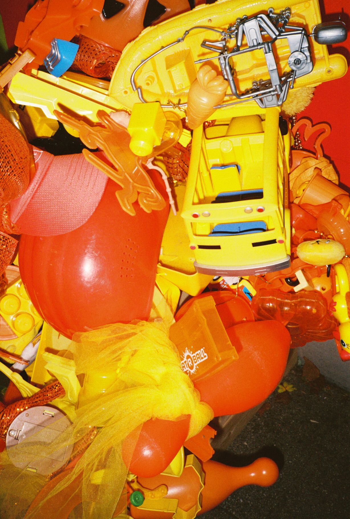 Collection of bright orange and yellow plastic toys or equipment arranged in a cluttered display.