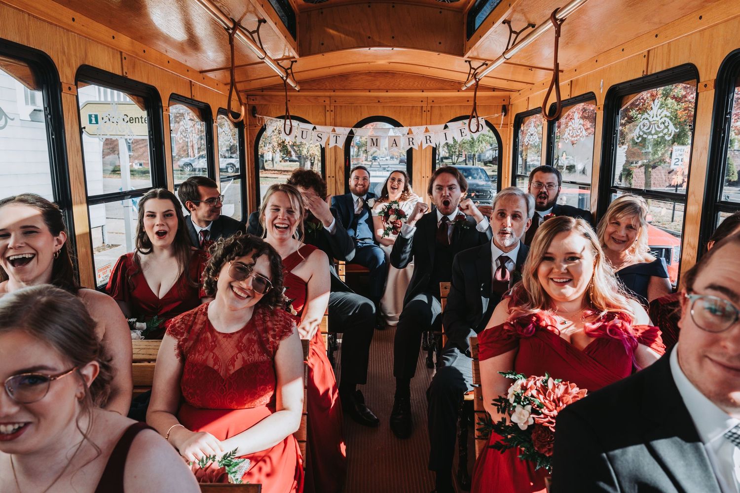 Wedding celebration inside a classic trolley bus with guests in formal attire.