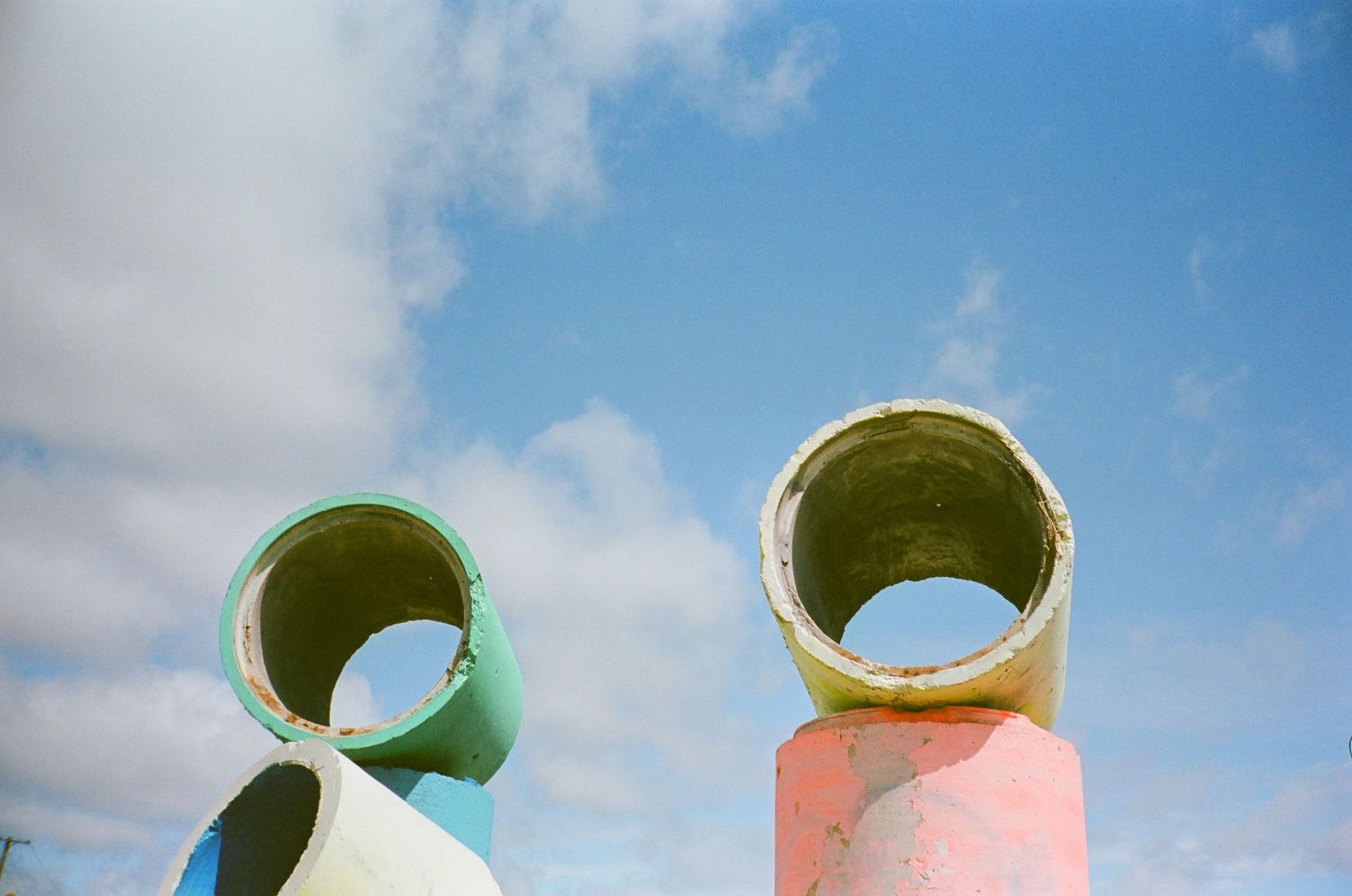 Curved colorful architectural elements against blue sky with white clouds.
