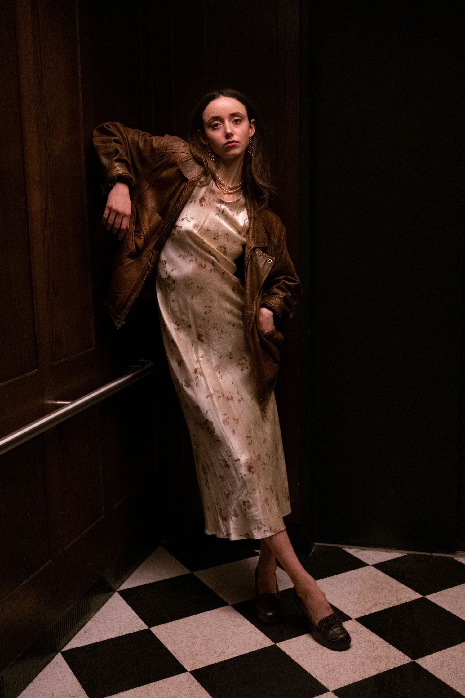 Dramatic portrait series on checkered floor with moody lighting and vintage styling.