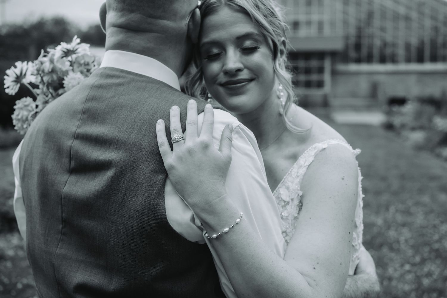 A tender moment captured in black and white showing hands clasped together during a wedding celebration.