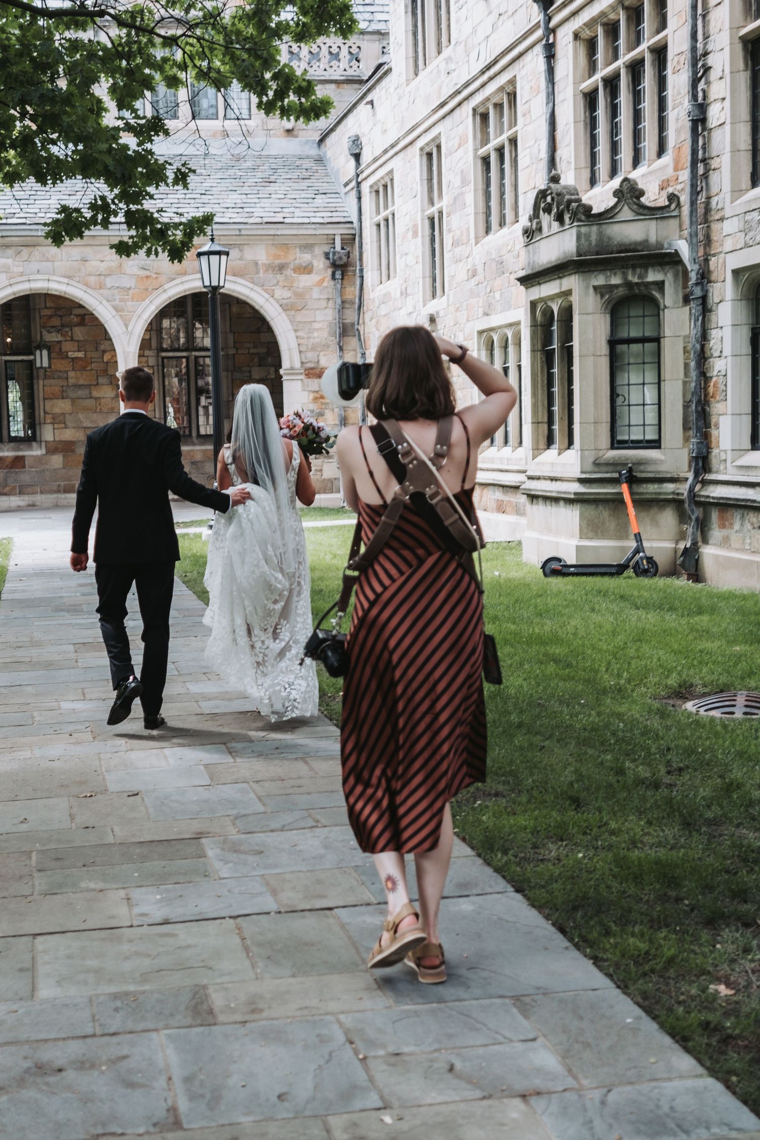 Wedding party walking along stone pathway outside historic building.
