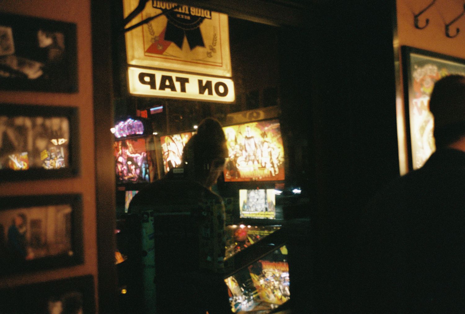 Illuminated neon signs and storefront windows glow in the dark at a city street corner.