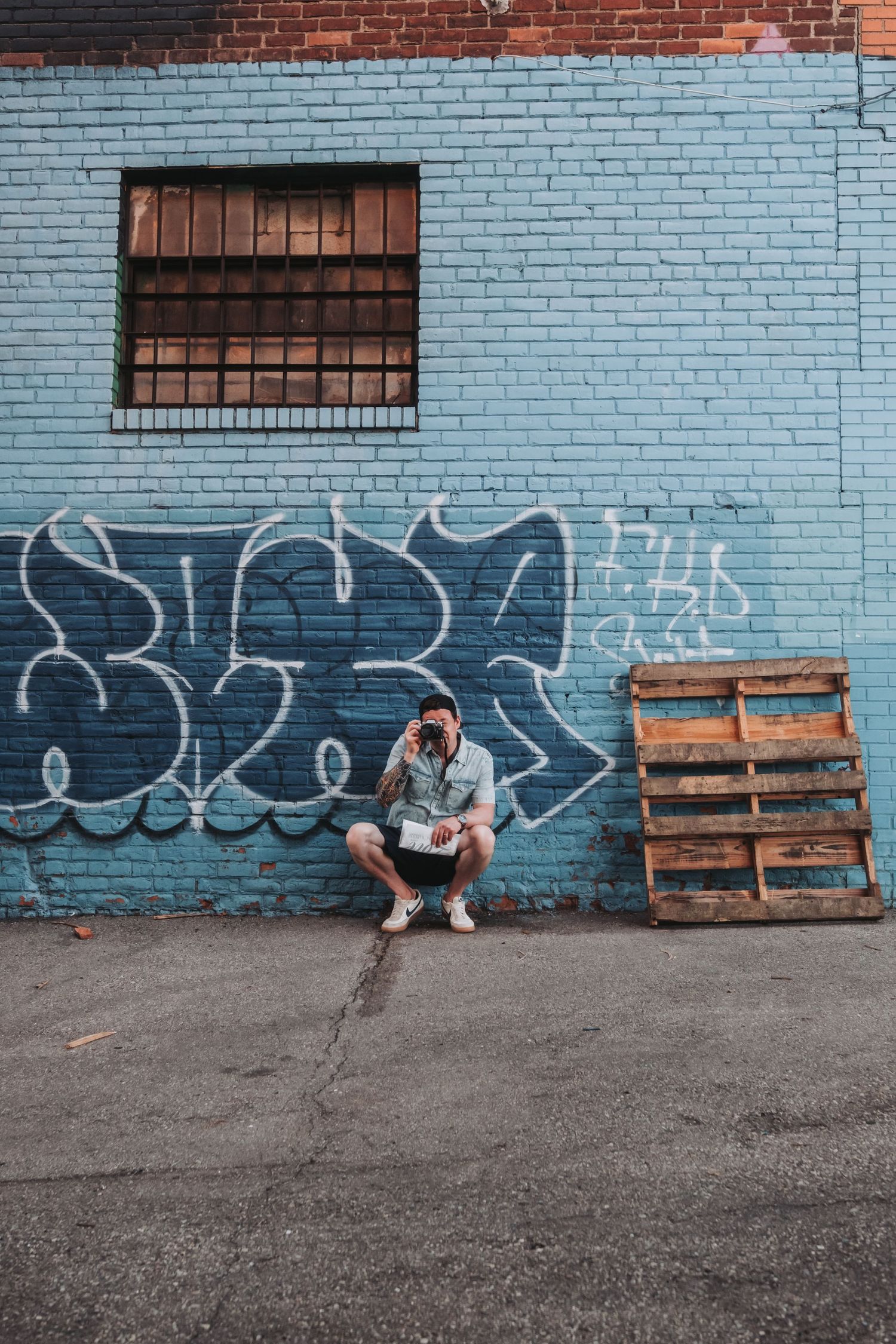 Urban scene with light blue painted brick wall and wooden pallets.