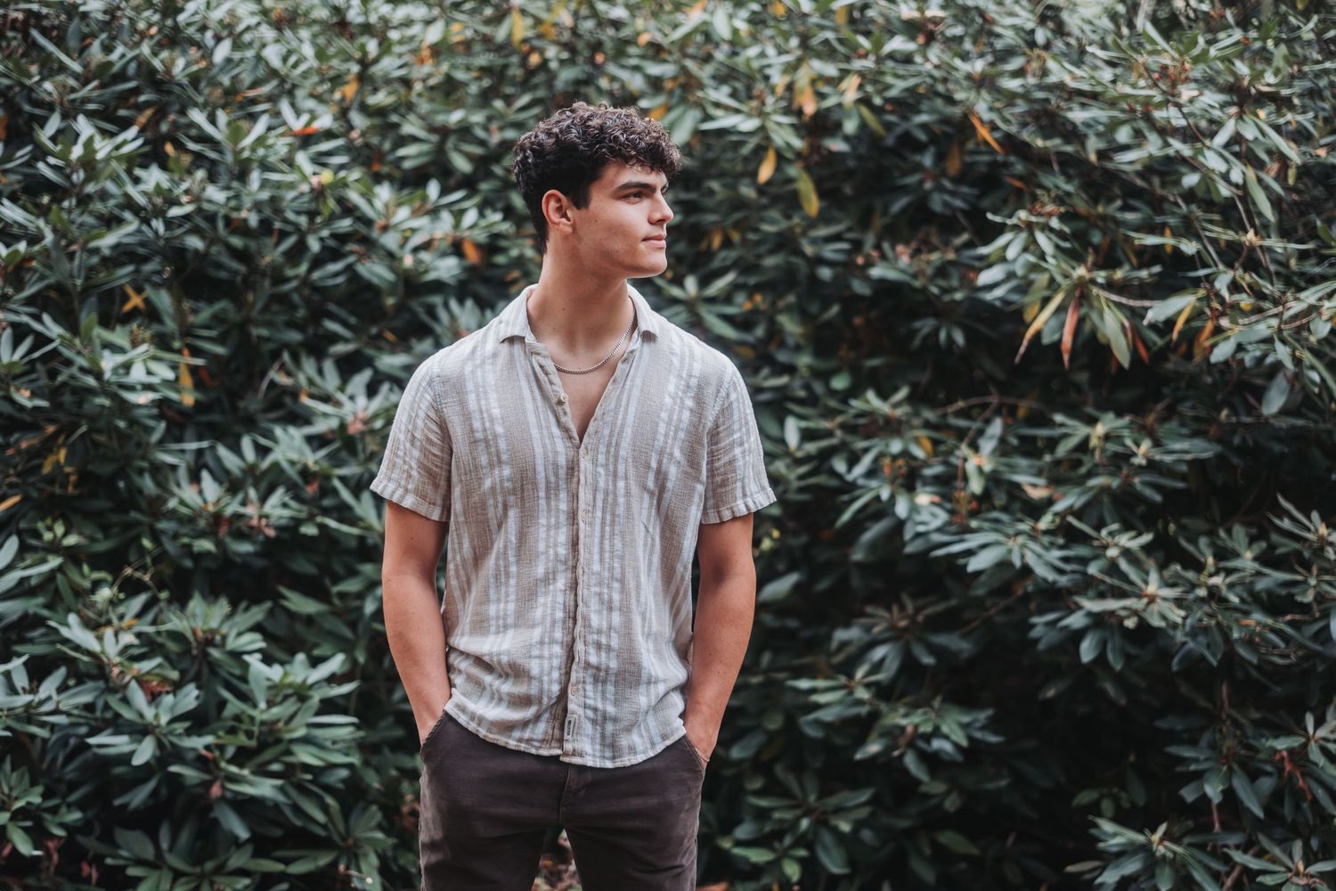 A person in casual attire stands against a leafy green backdrop in a vintage-style photo series.