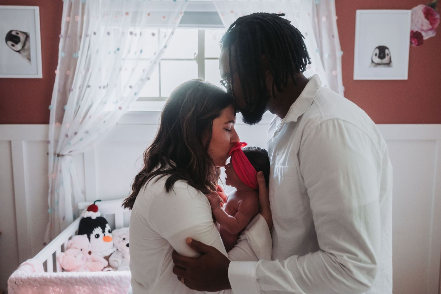 Intimate moment between couple sharing red rose in nursery room with white curtains.