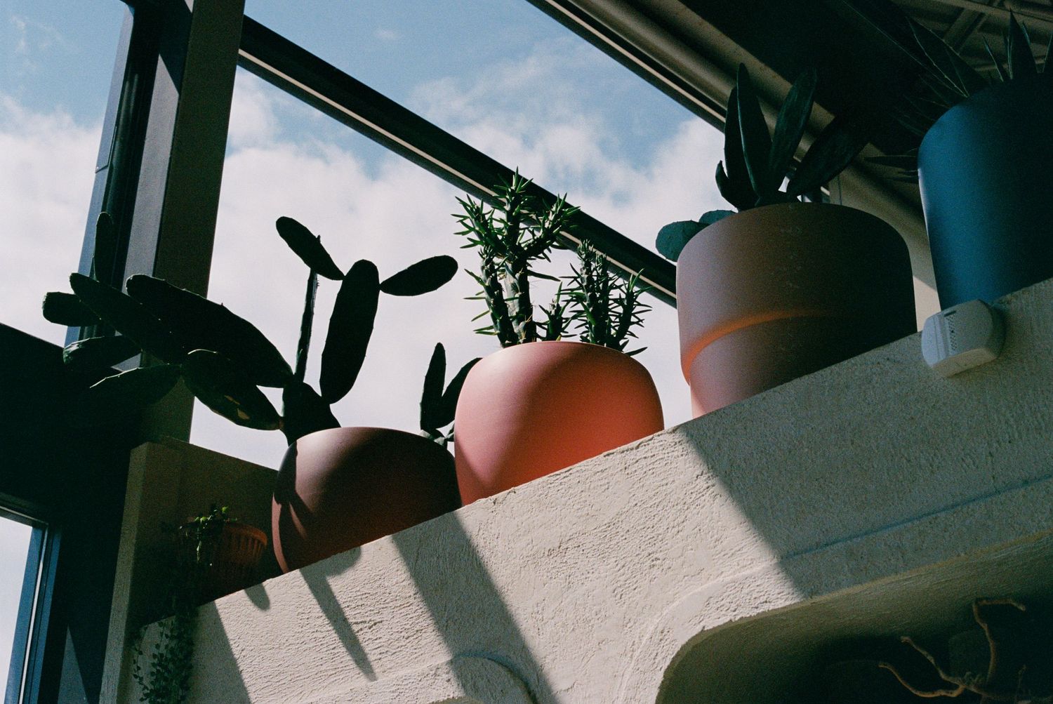 Terracotta pots casting dramatic shadows against bright sky.