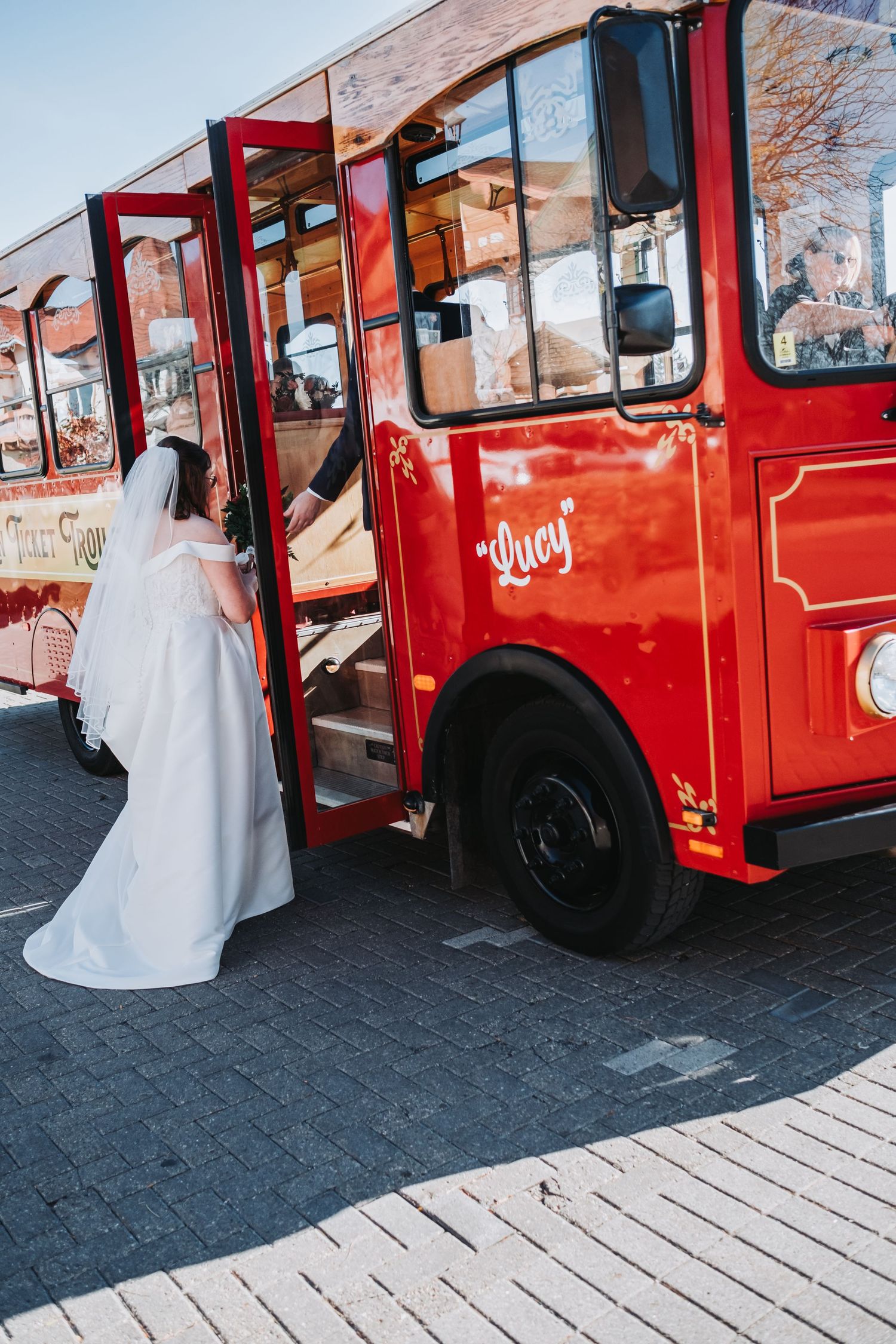 Red trolley bus parked on a cobblestone street with flowing white fabric visible.