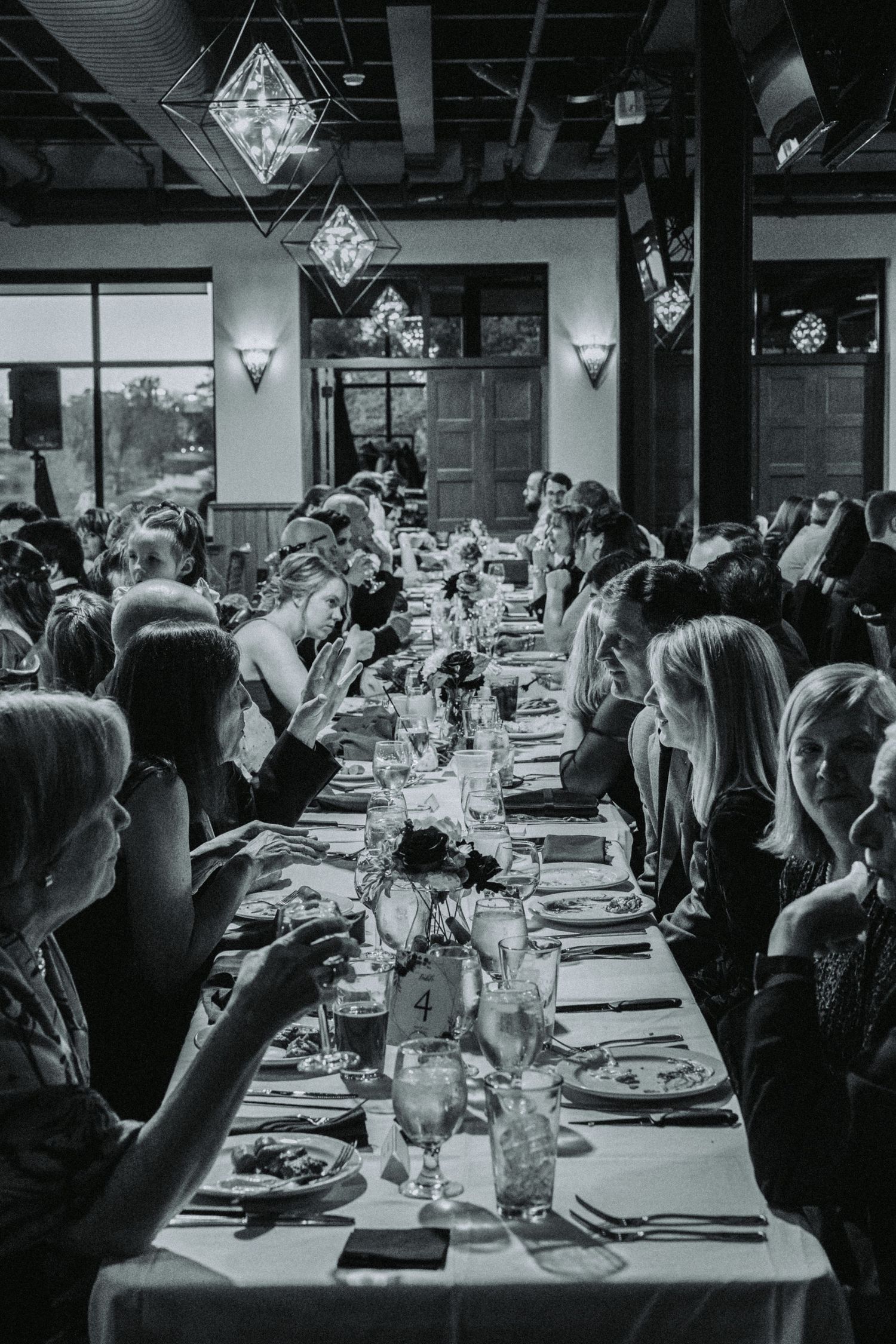 Black and white photograph of a formal dining event with long tables and gathered guests.