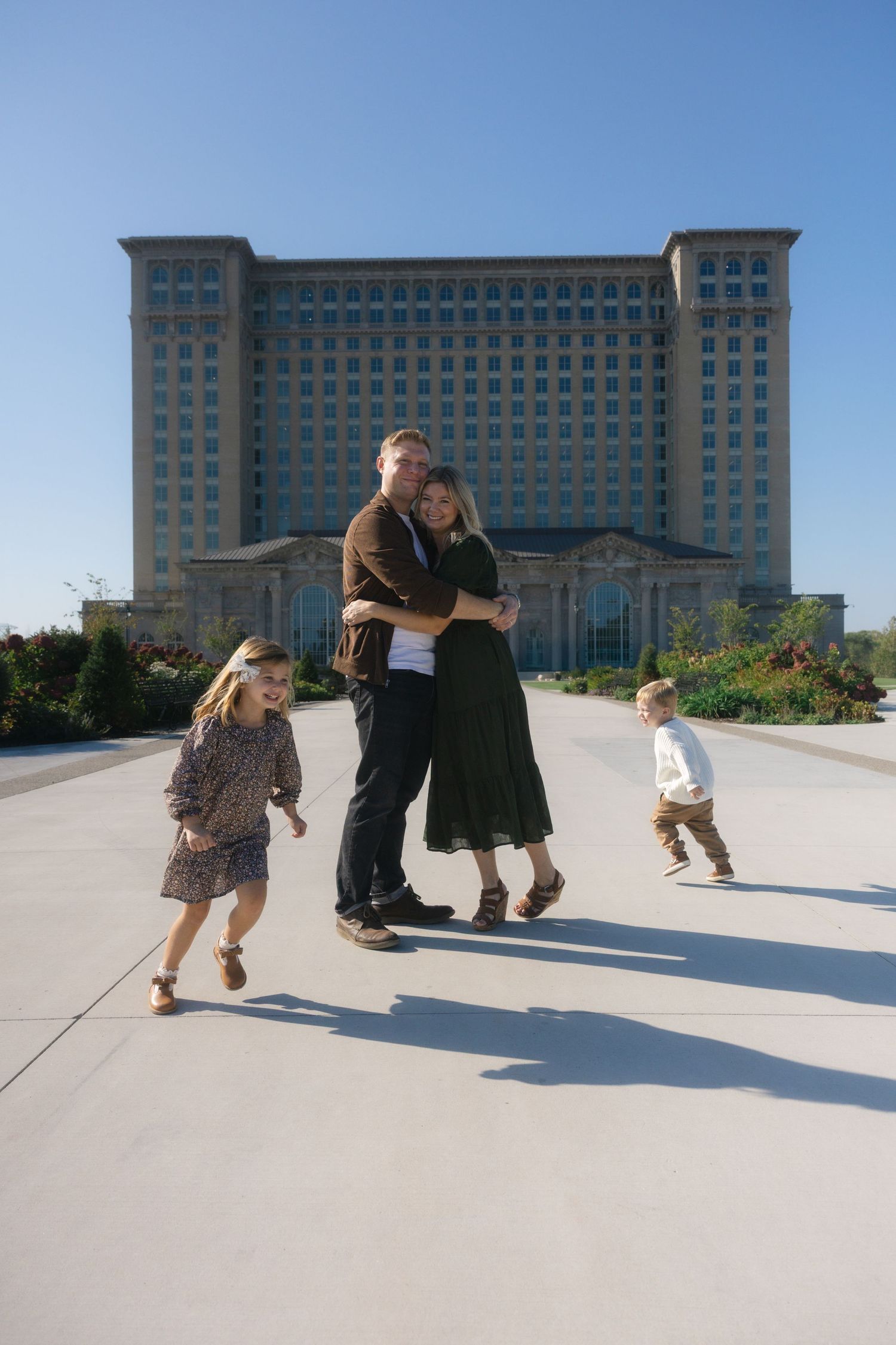 A sequence of playful silhouettes cast long shadows while running and playing on a concrete plaza near a modern office building.