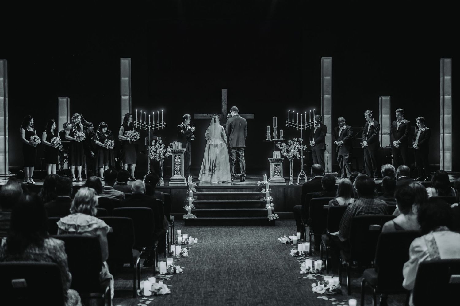 Dark auditorium or theater space with silhouettes of people seated in rows.