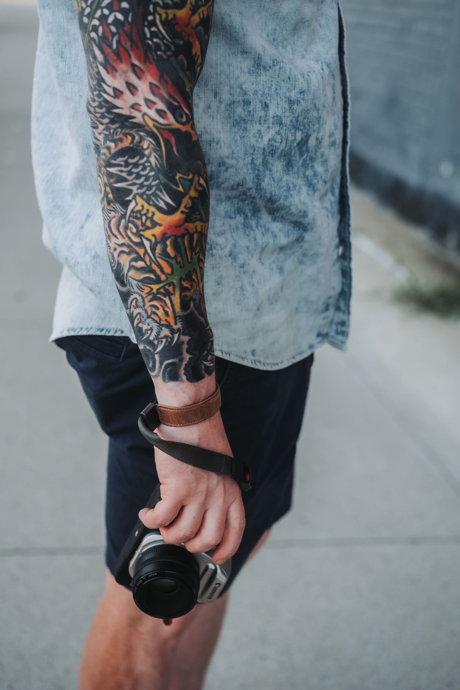 Close-up view of a colorful dragon tattoo sleeve on someone's arm.