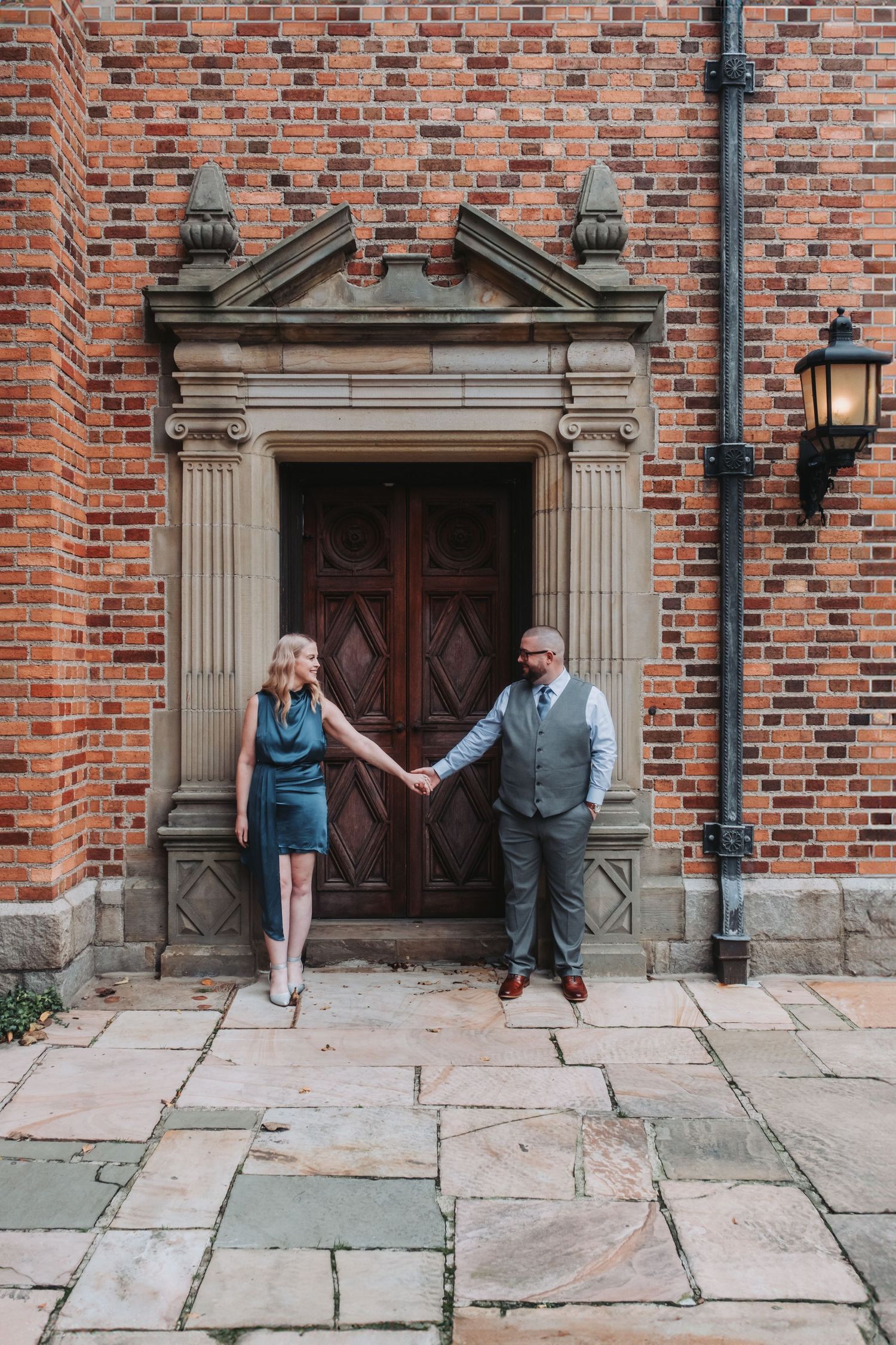 Historic brick building entrance with ornate stone doorway and people posing playfully.