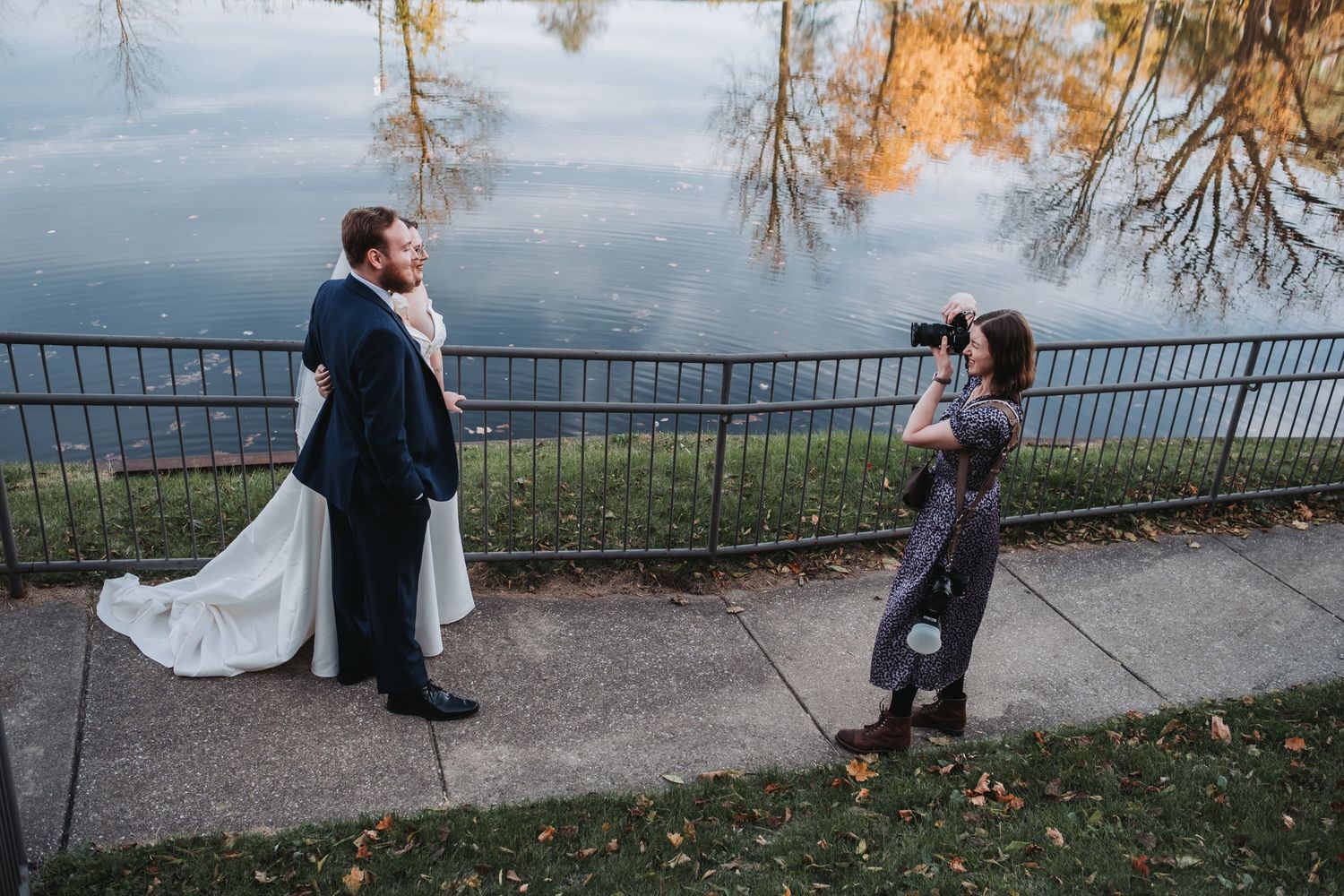 Wedding couple and photographer on scenic overlook during sunset photoshoot.