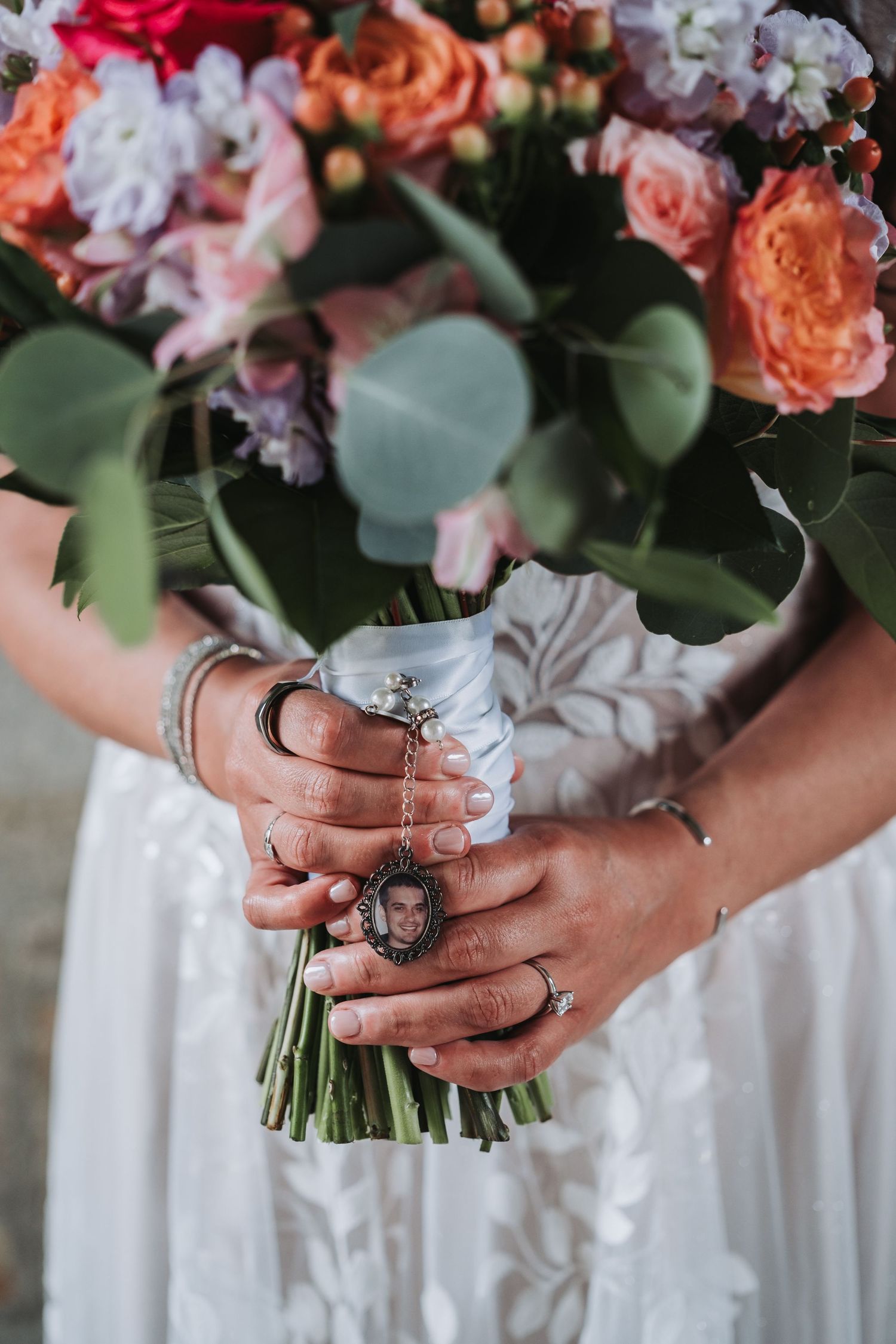Close-up of hands holding colorful bridal bouquet with statement rings.