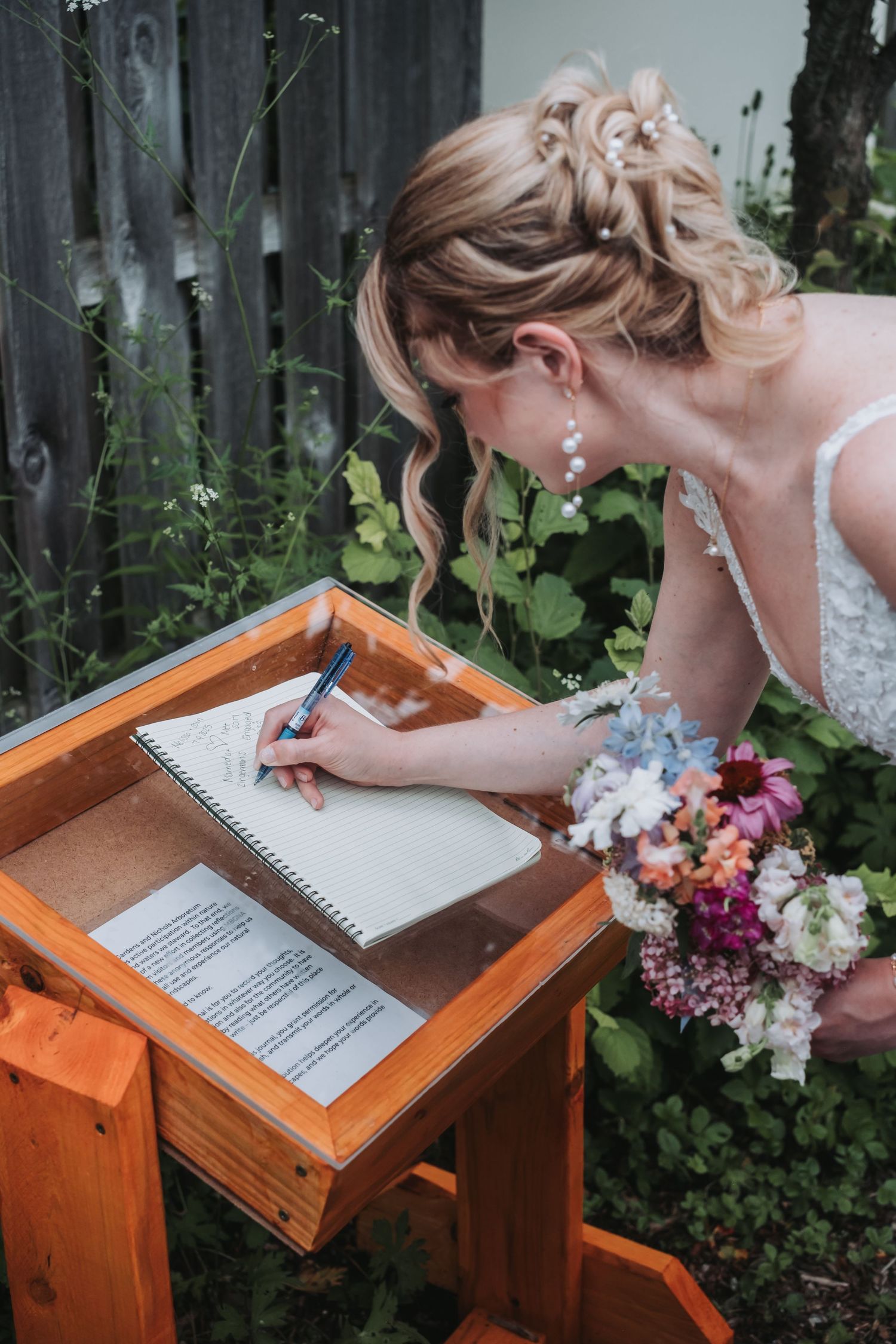 Wedding scene featuring a wooden signing table with a colorful floral bouquet.