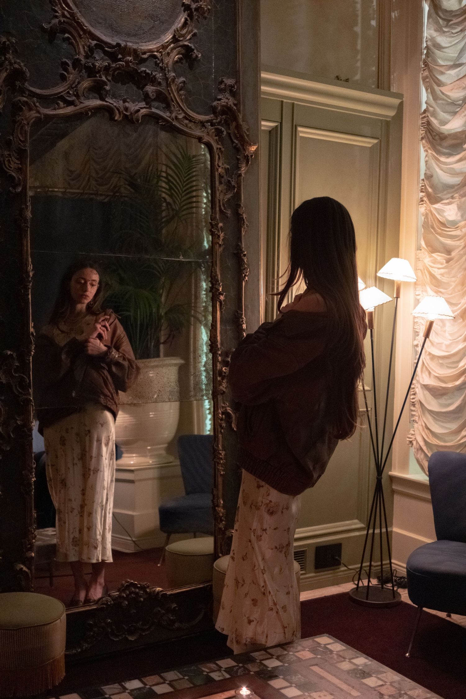 Elegant photo series with person posing near ornate antique mirror in dark room.