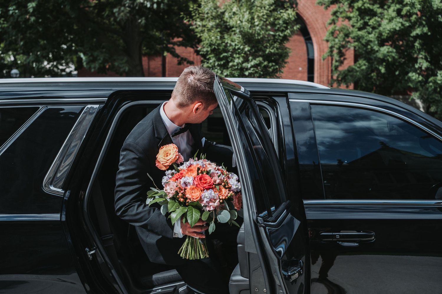 Black luxury wedding transportation vehicle parked outside venue.