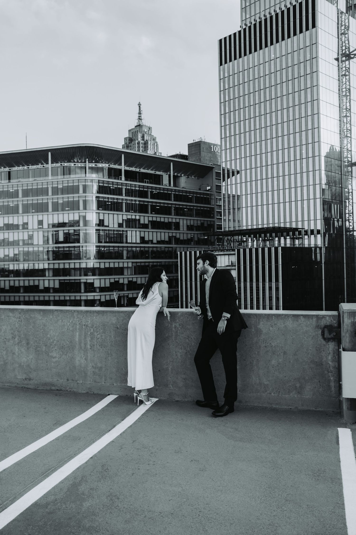 Black and white photo of a bride and groom sharing a romantic moment on a rooftop with city skyscrapers behind them.