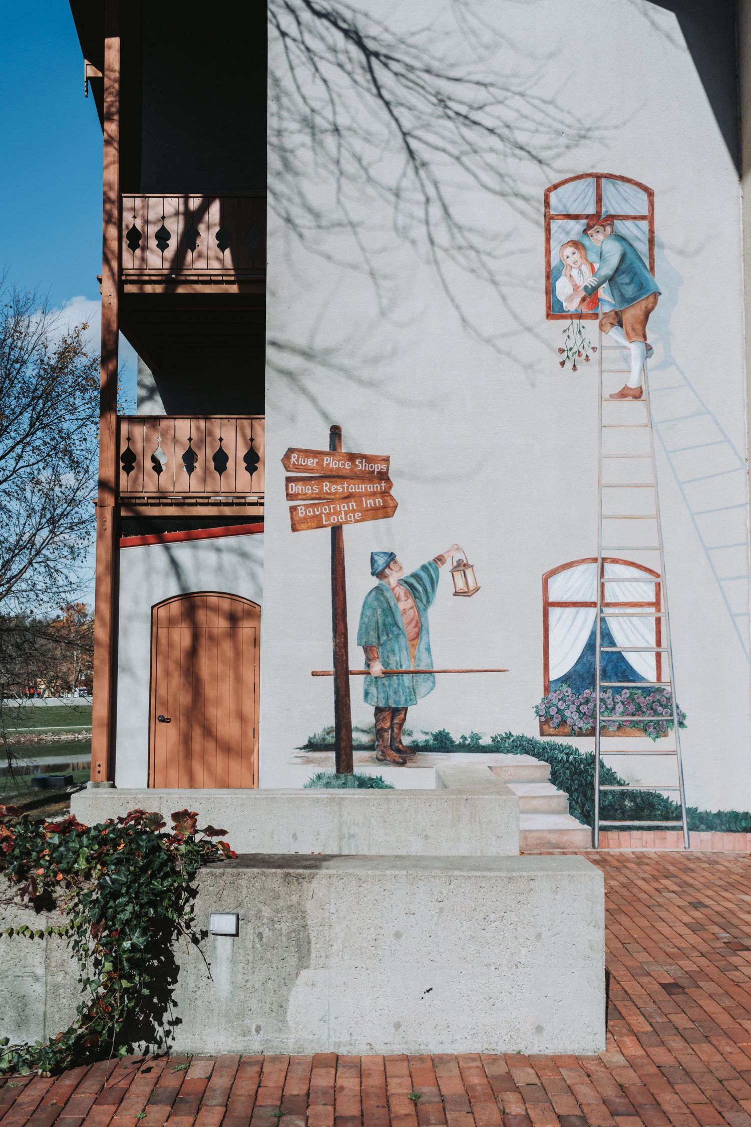 Whimsical mural depicting figures and ladders painted on white building wall.