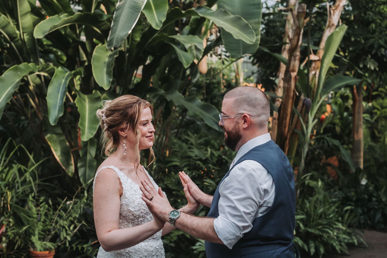 Wedding couple sharing an emotional moment among tropical plants and greenery.