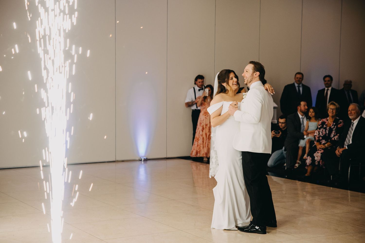Bride and groom share first dance with sparkling cold sparkler fountains at elegant wedding reception.