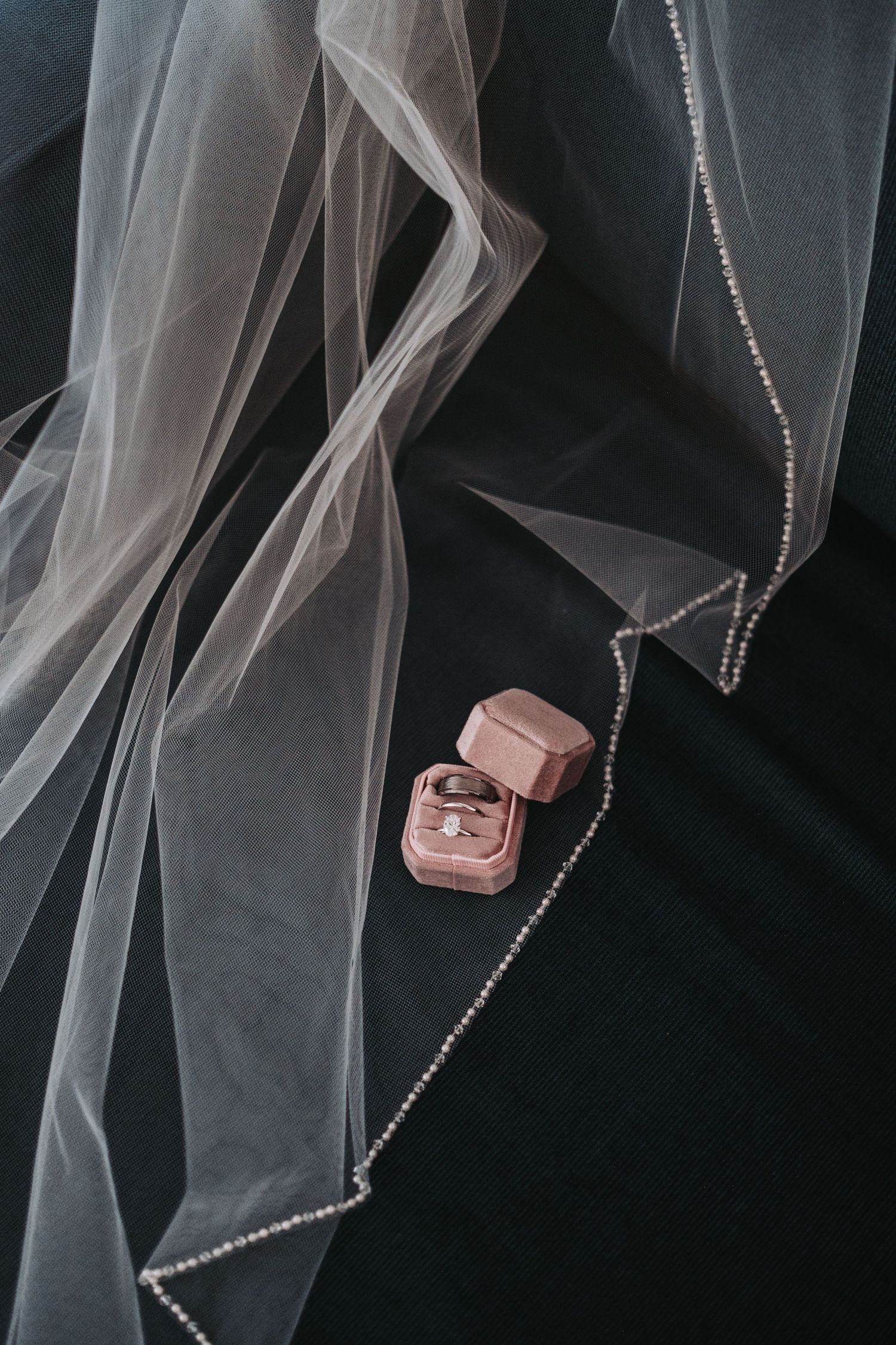 Wedding veil with delicate beading detail against dark background.