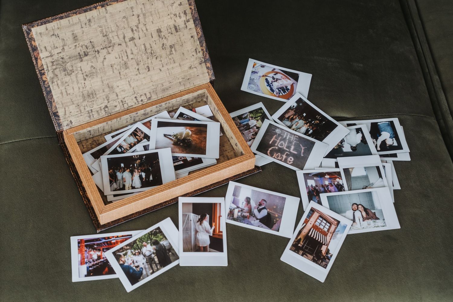 Vintage wooden box surrounded by scattered Polaroid photos on a green surface, capturing cherished memories.