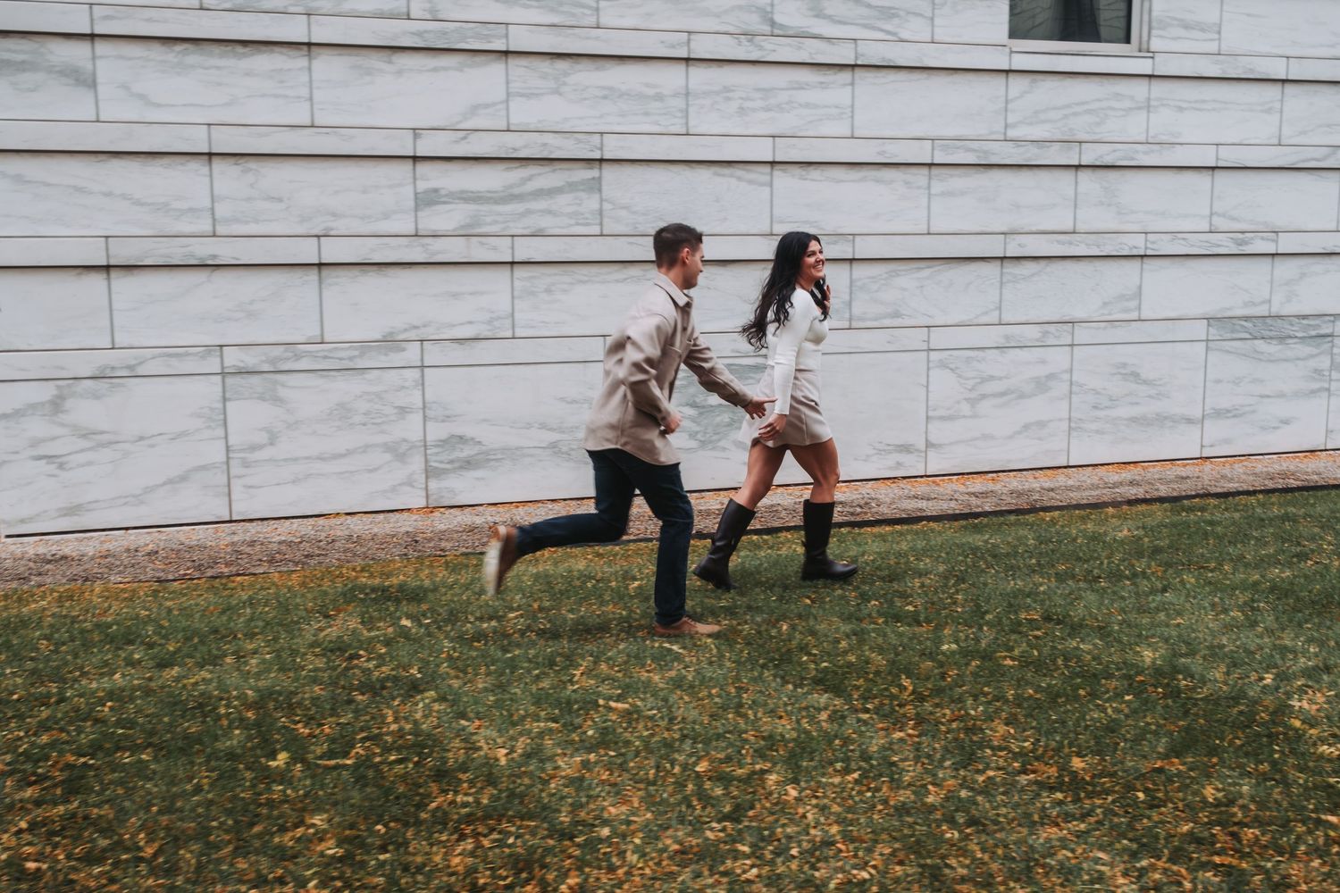 People playing on a grassy lawn outside a modern building.