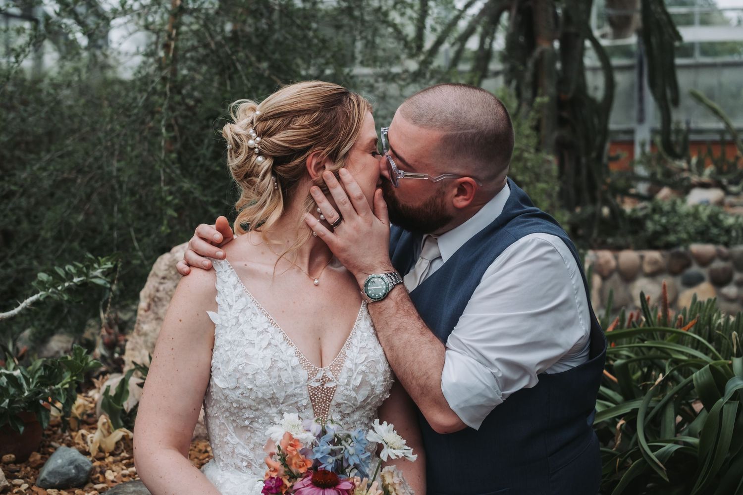 Intimate wedding moment captured among lush garden foliage.