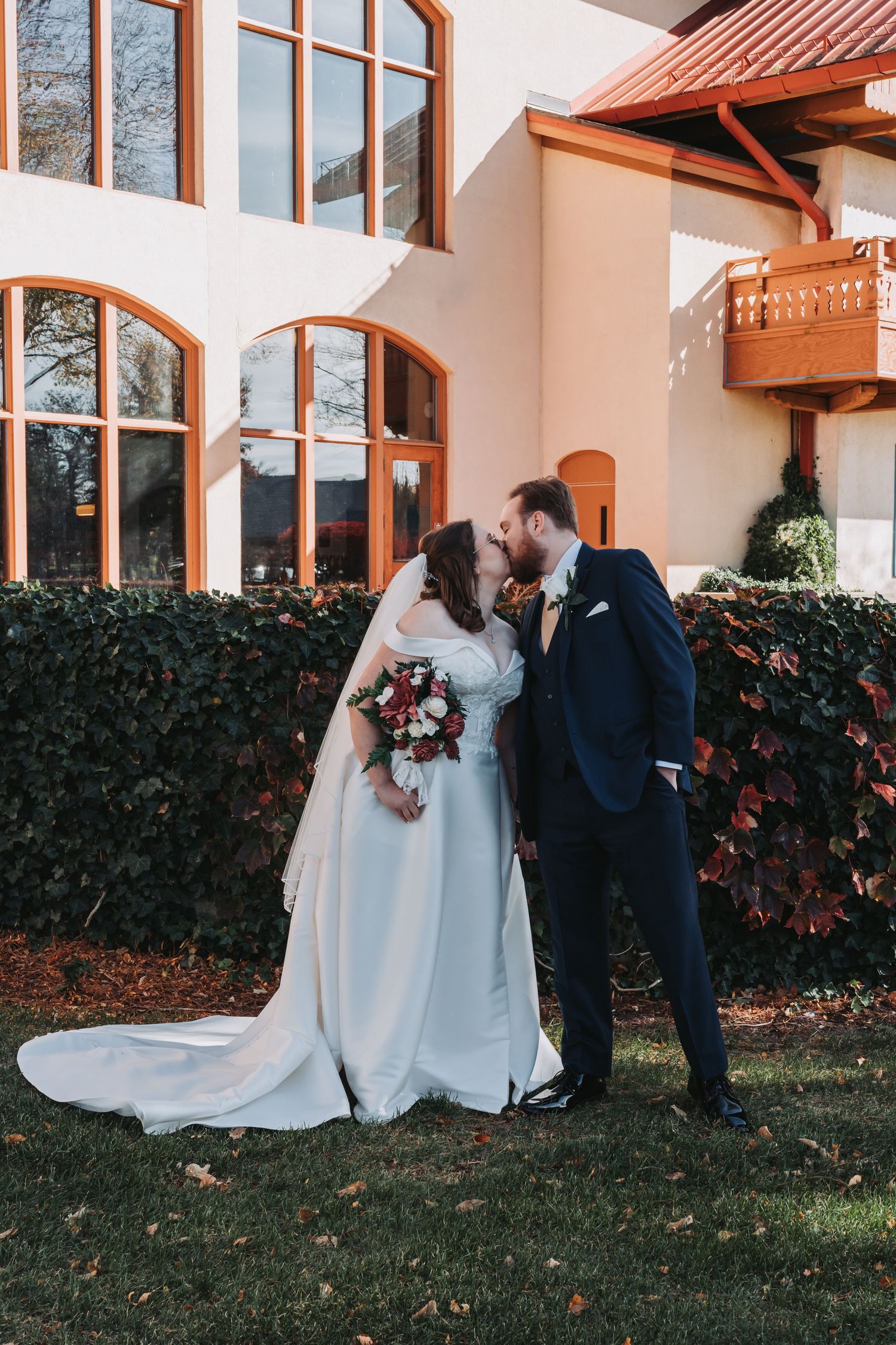 Wedding couple posing outside a building with terracotta roof and white walls.
