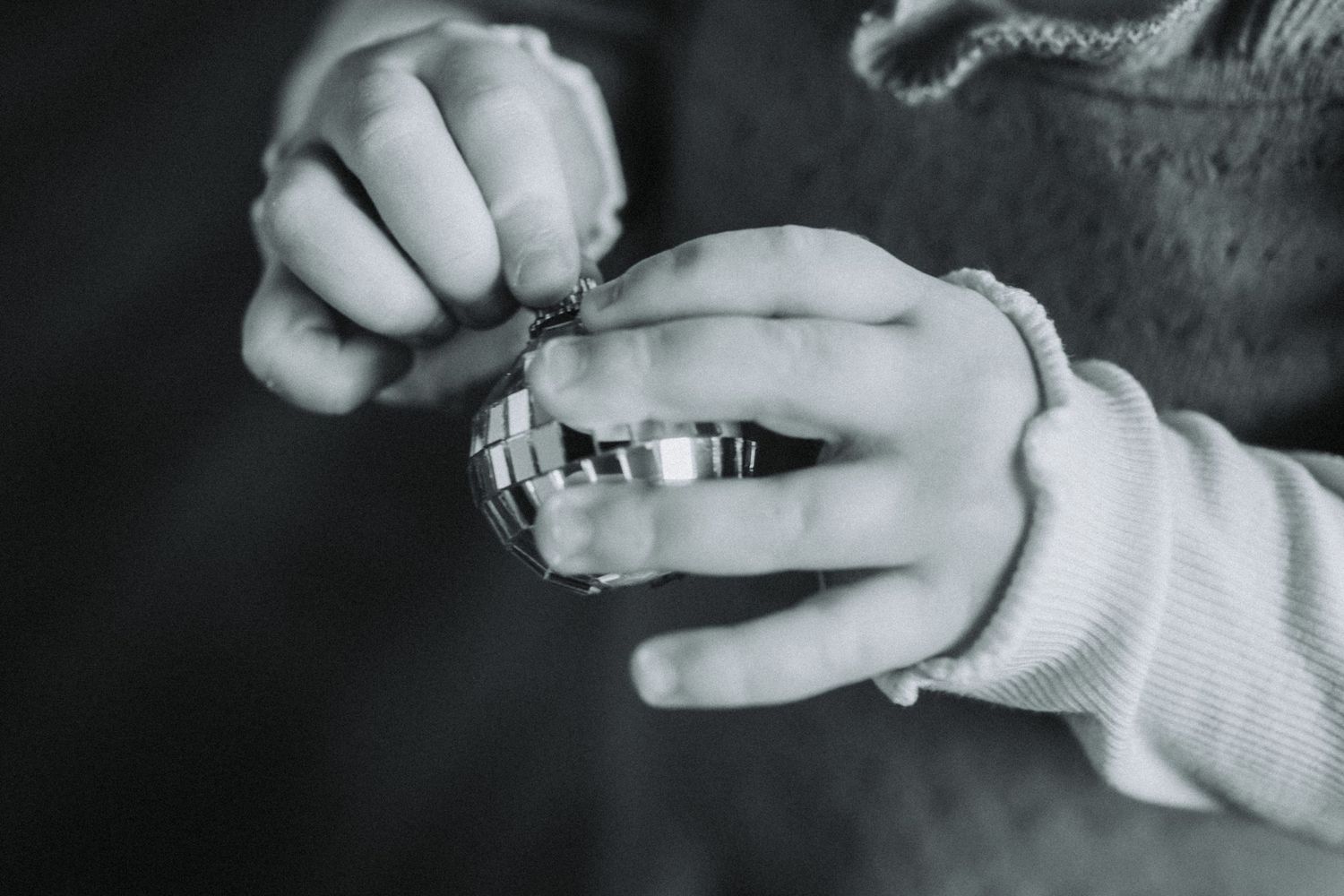 Hands hold wedding rings in black and white photography.