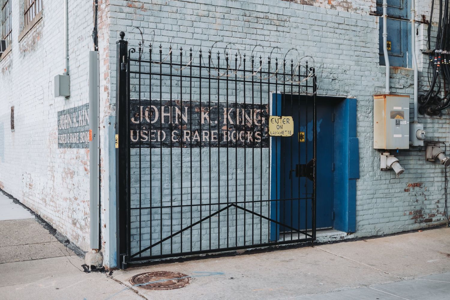 Gated storefront entrance with 'John R. King Used & Rare Books' signage.