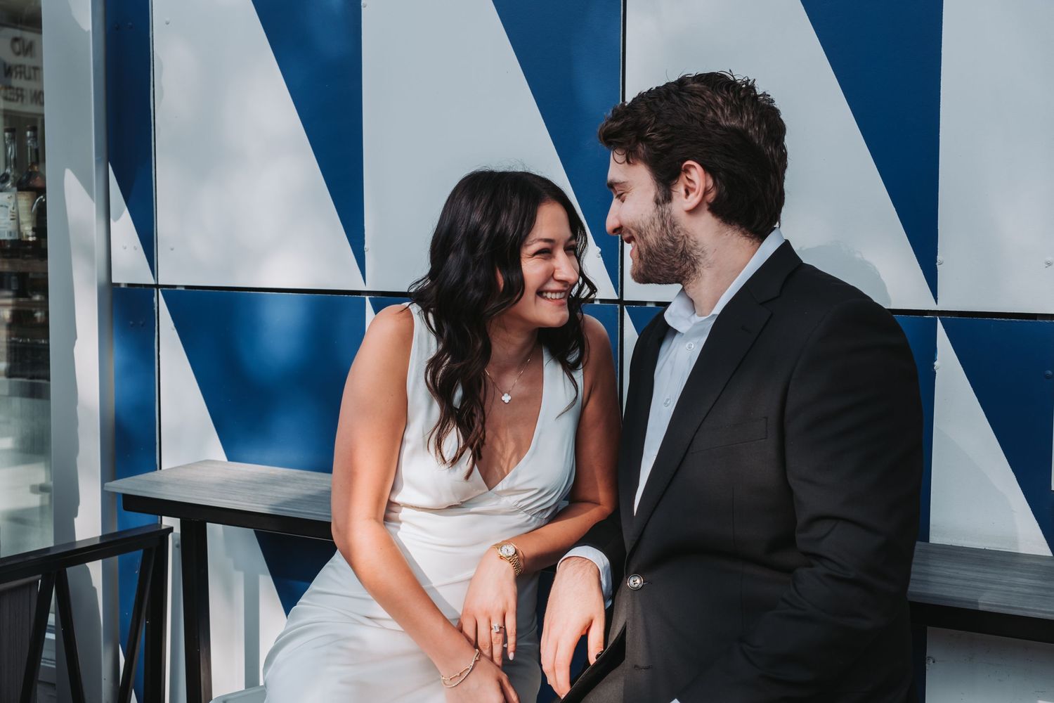 Wedding couple sharing intimate moment against blue and white geometric background.