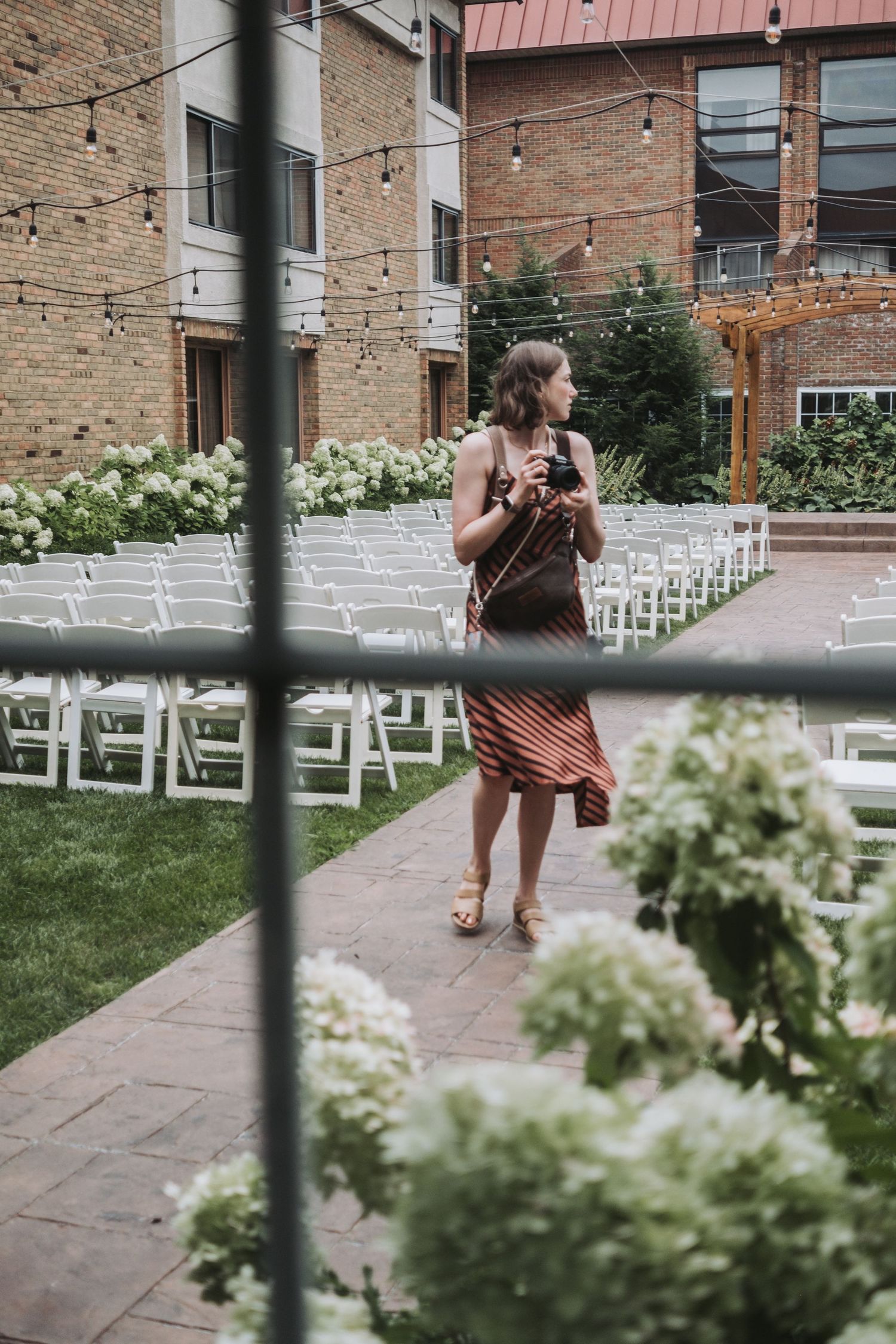 Outdoor wedding venue setup with white chairs and floral decorations.