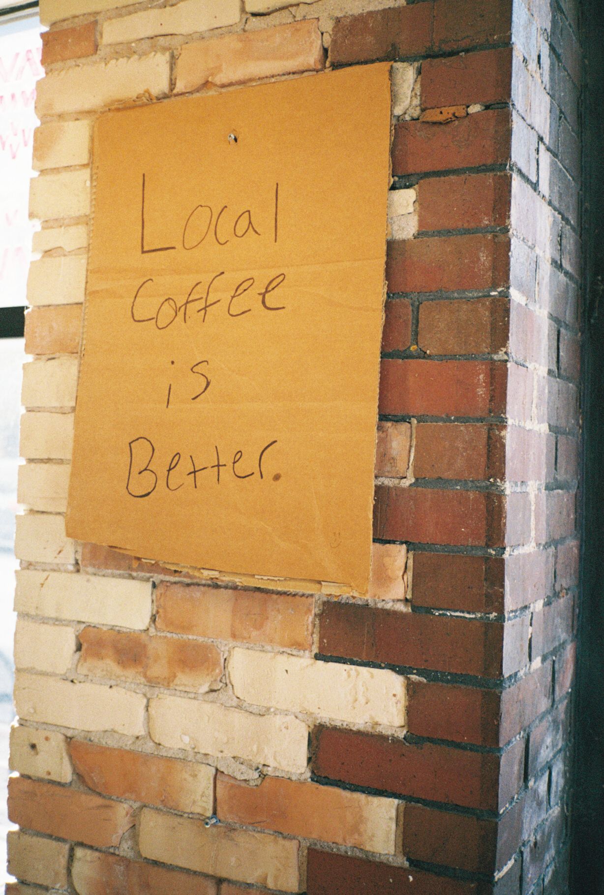Brown cardboard signs with handwritten text mounted on a brick wall in sequence.