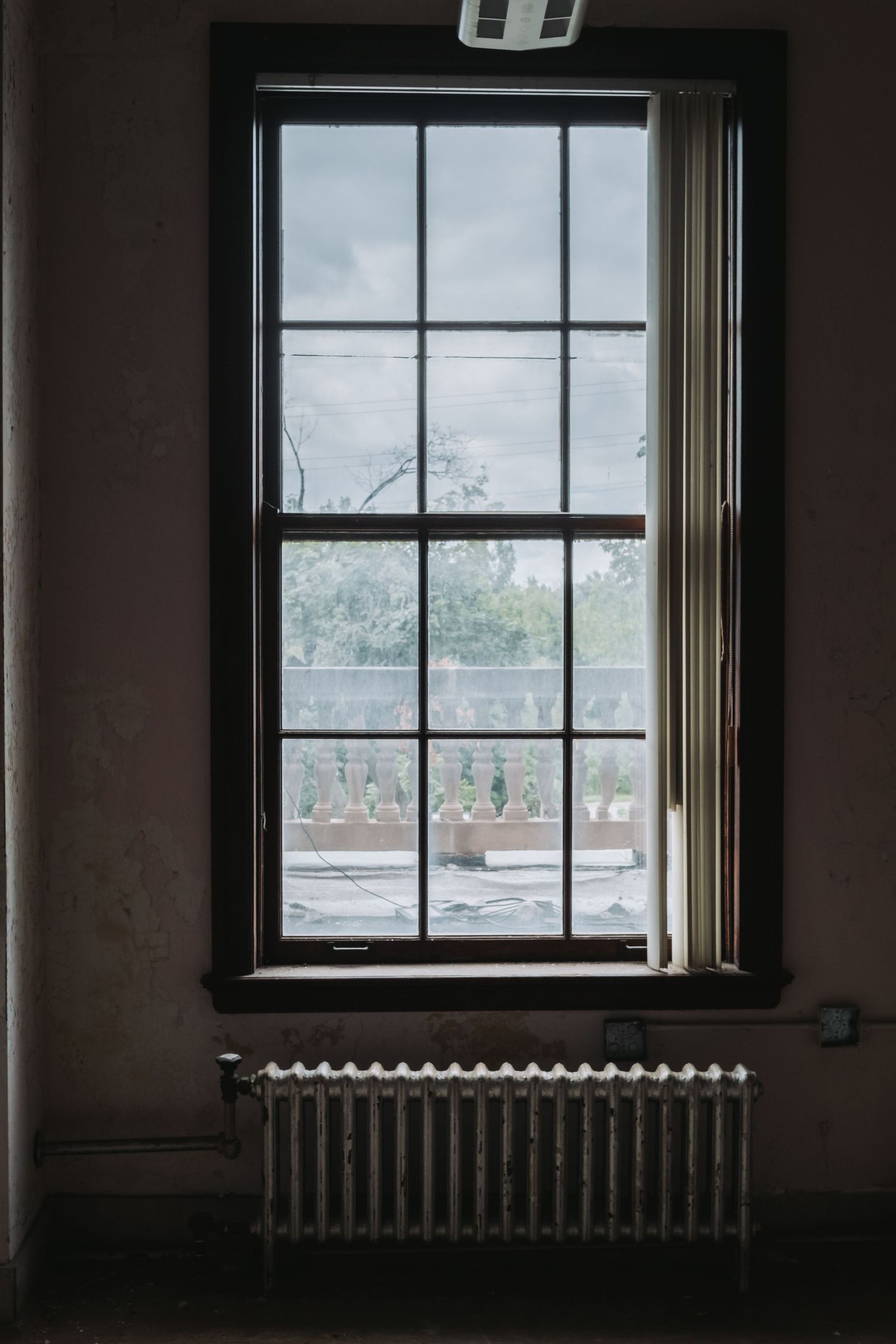 Dark interior room with window showing view of buildings outside.
