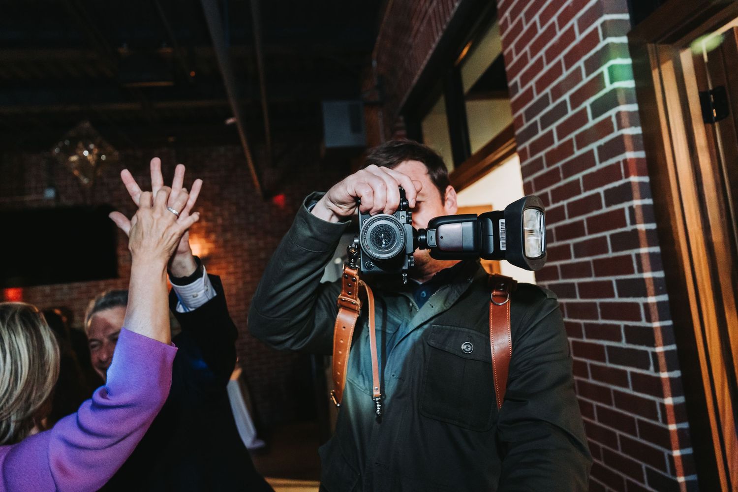 Wedding photographers working in dark indoor venue with camera equipment.