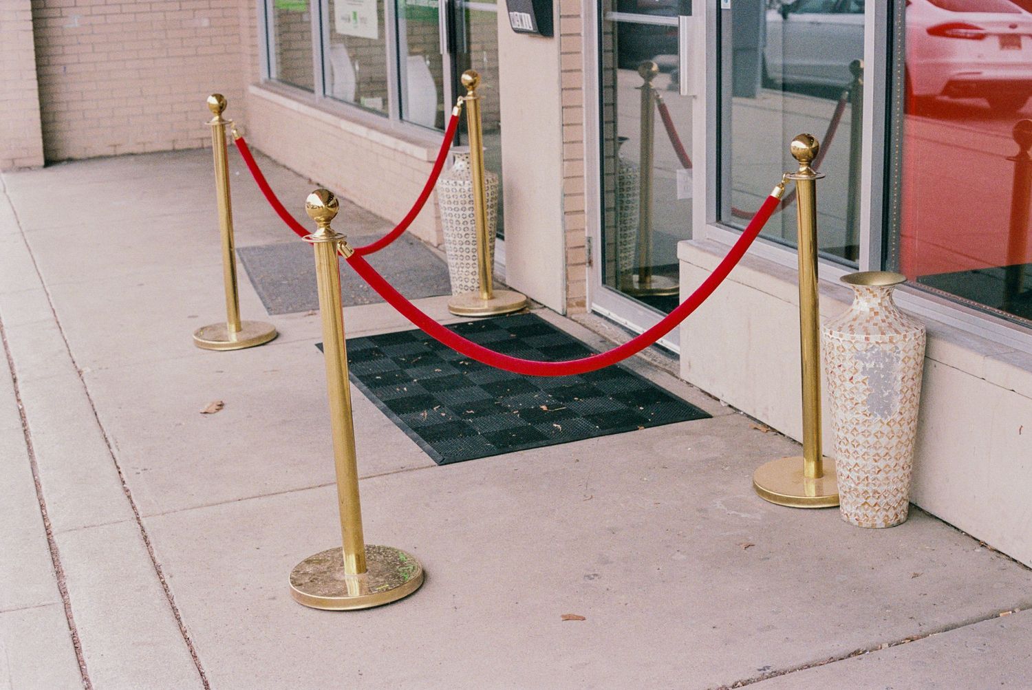 Gold stanchion posts with red velvet ropes arranged in front of a building entrance.