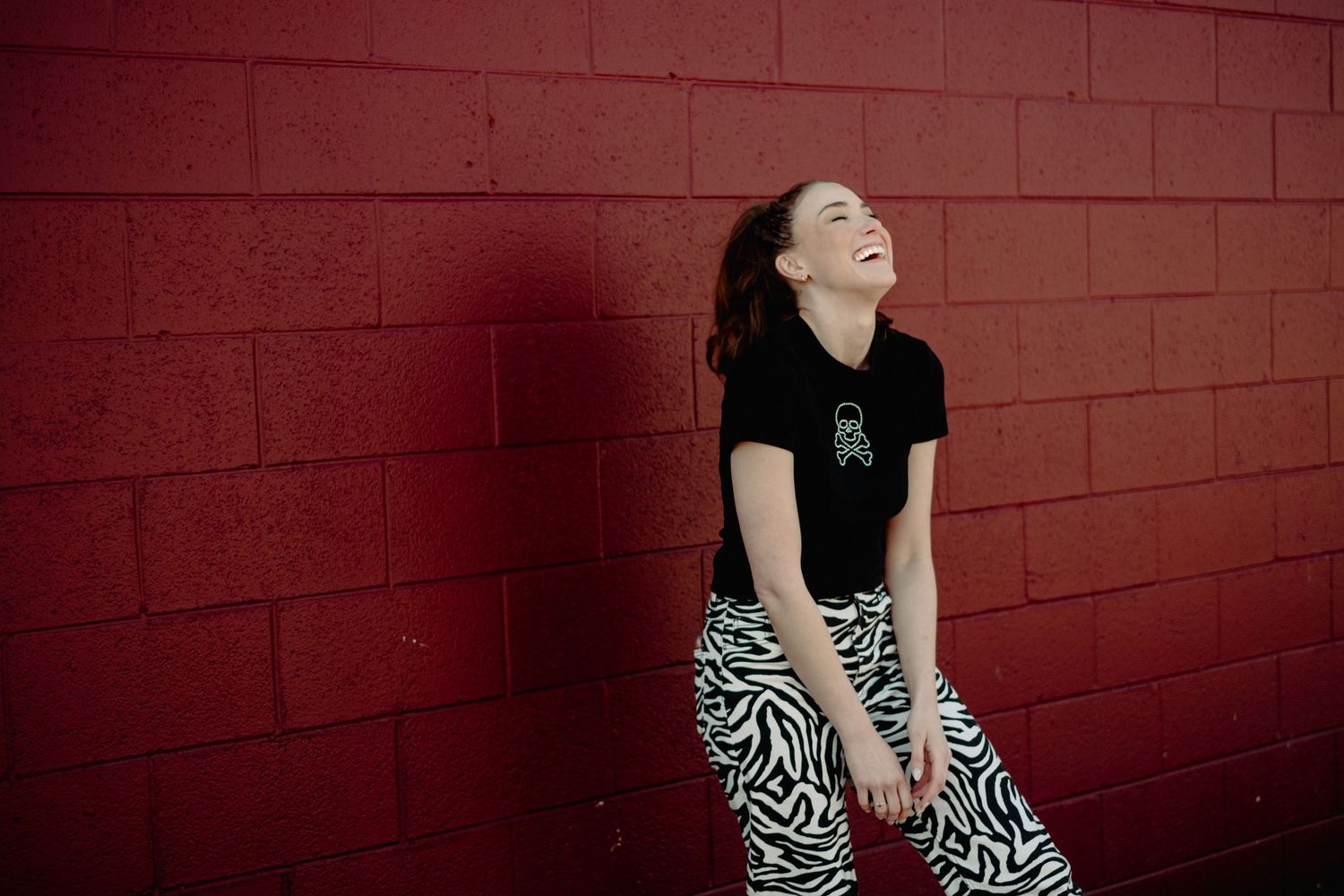 Person in black shirt poses expressively against red brick wall in progressive sequence.