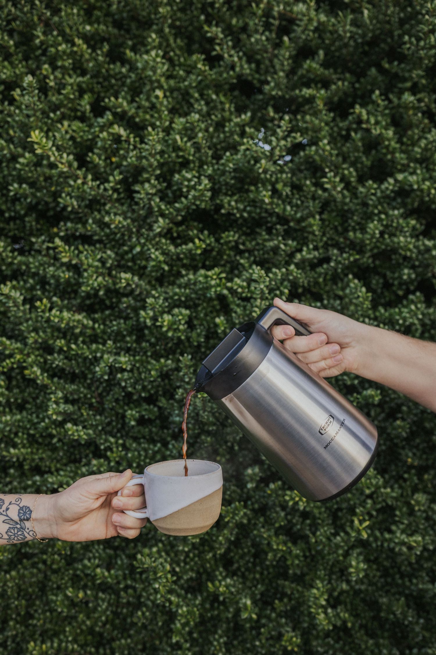 Step-by-step demonstration of pouring hot coffee from thermos into cup outdoors.