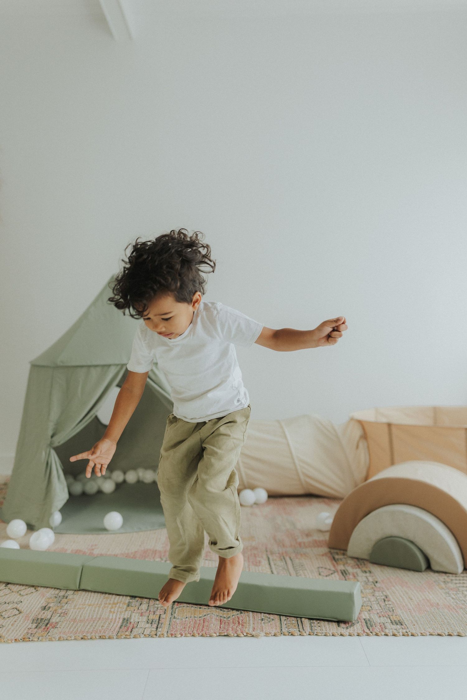 Candid shots of playtime with white balls and a sage green tent in a bright room.