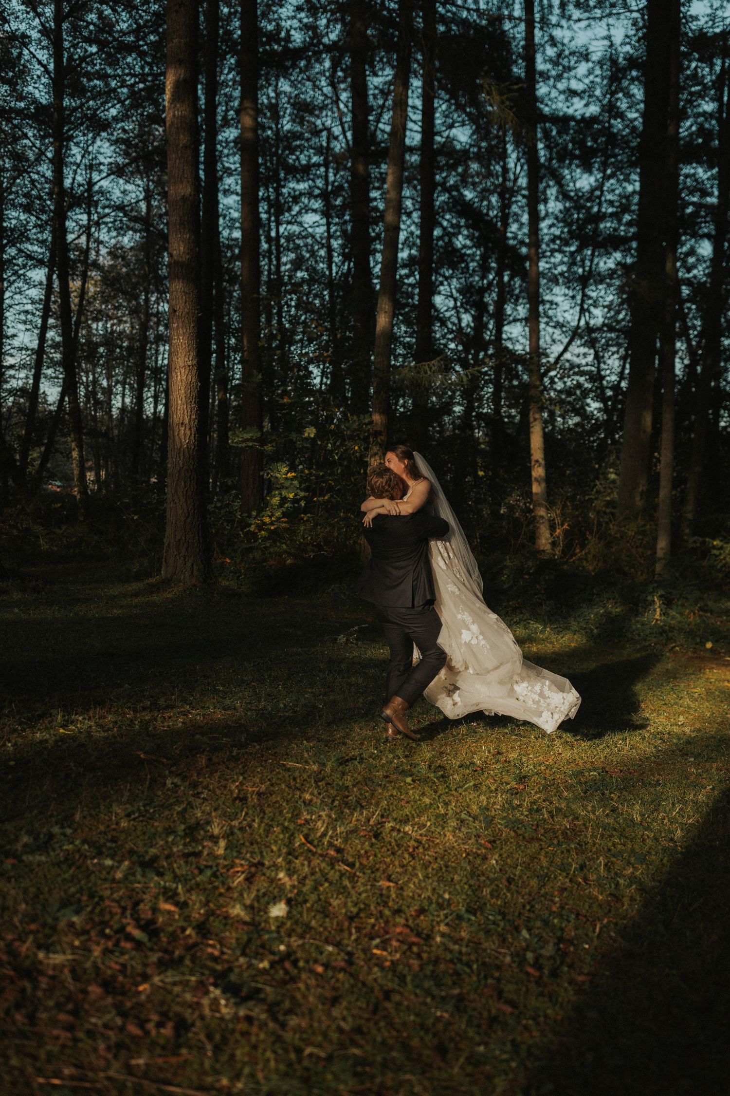 A romantic wedding photo session in a moody forest setting with fallen leaves.