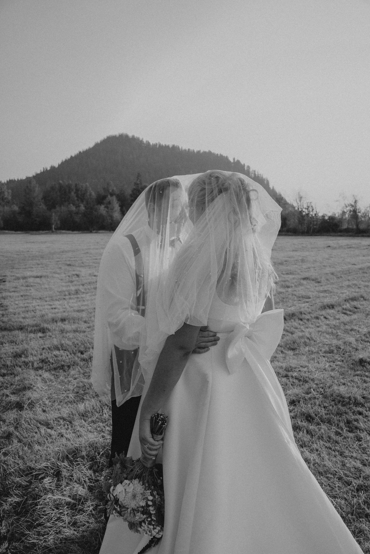 Black and white wedding portrait in a scenic mountain meadow.